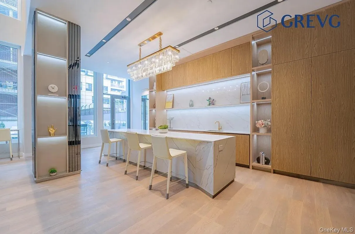 Kitchen featuring modern cabinets, a breakfast bar, open shelves, light stone countertops, and decorative light fixtures Kitchen featuring modern cabinets, a breakfast bar, open shelves, light stone countertops, and decorative light fixtures