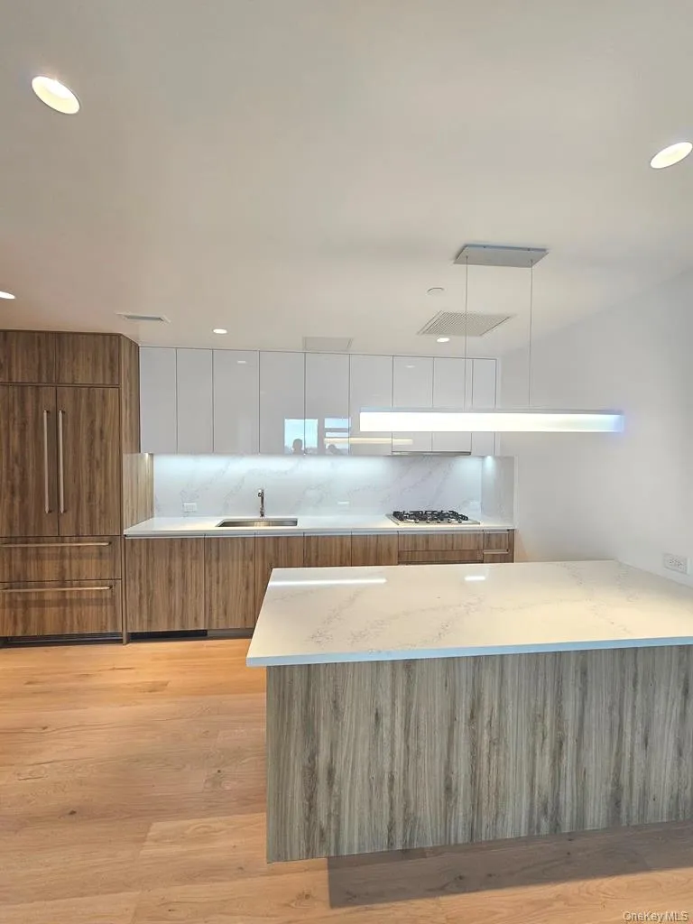 Kitchen with brown cabinets, modern cabinets, white cabinets, light stone countertops, and light wood-style flooring Kitchen with brown cabinets, modern cabinets, white cabinets, light stone countertops, and light wood-style flooring