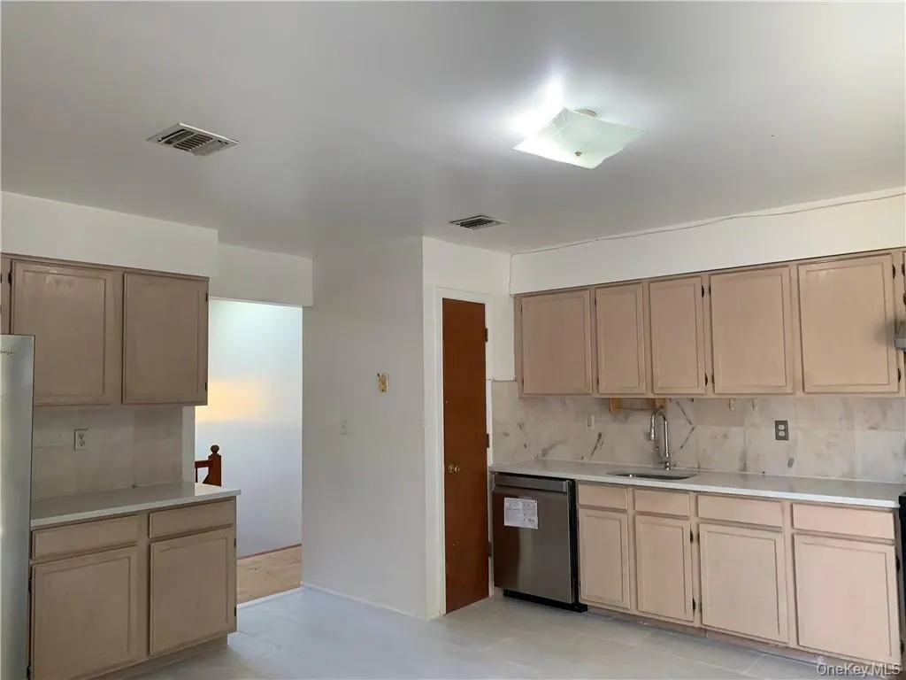 Kitchen with tasteful backsplash, light brown cabinetry, sink, light tile patterned flooring, and stainless steel appliances Kitchen with tasteful backsplash, light brown cabinetry, sink, light tile patterned flooring, and stainless steel appliances