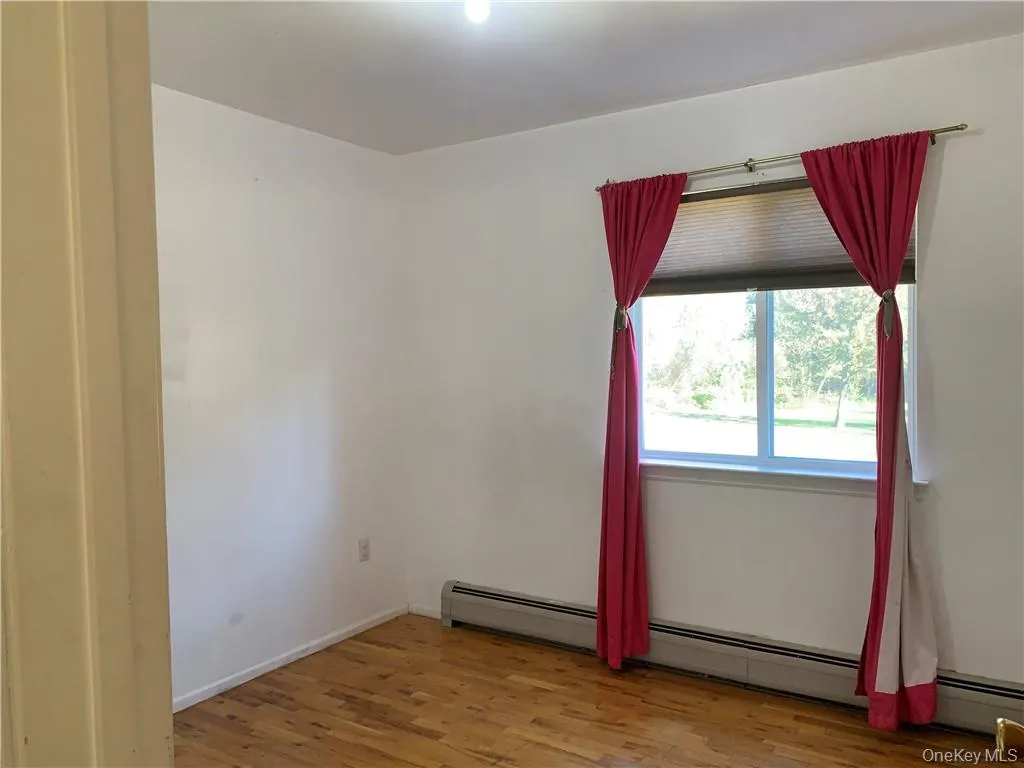 Spare room featuring a baseboard heating unit and hardwood / wood-style floors Spare room featuring a baseboard heating unit and hardwood / wood-style floors
