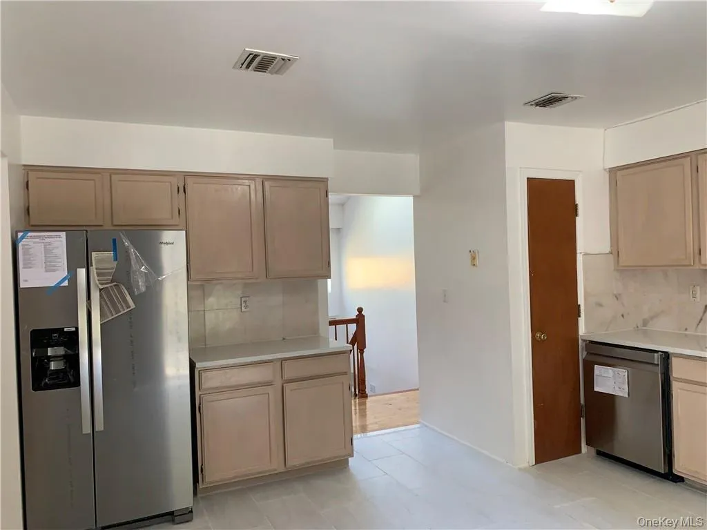 Kitchen featuring light brown cabinetry, appliances with stainless steel finishes, backsplash, and light tile patterned flooring Kitchen featuring light brown cabinetry, appliances with stainless steel finishes, backsplash, and light tile patterned flooring