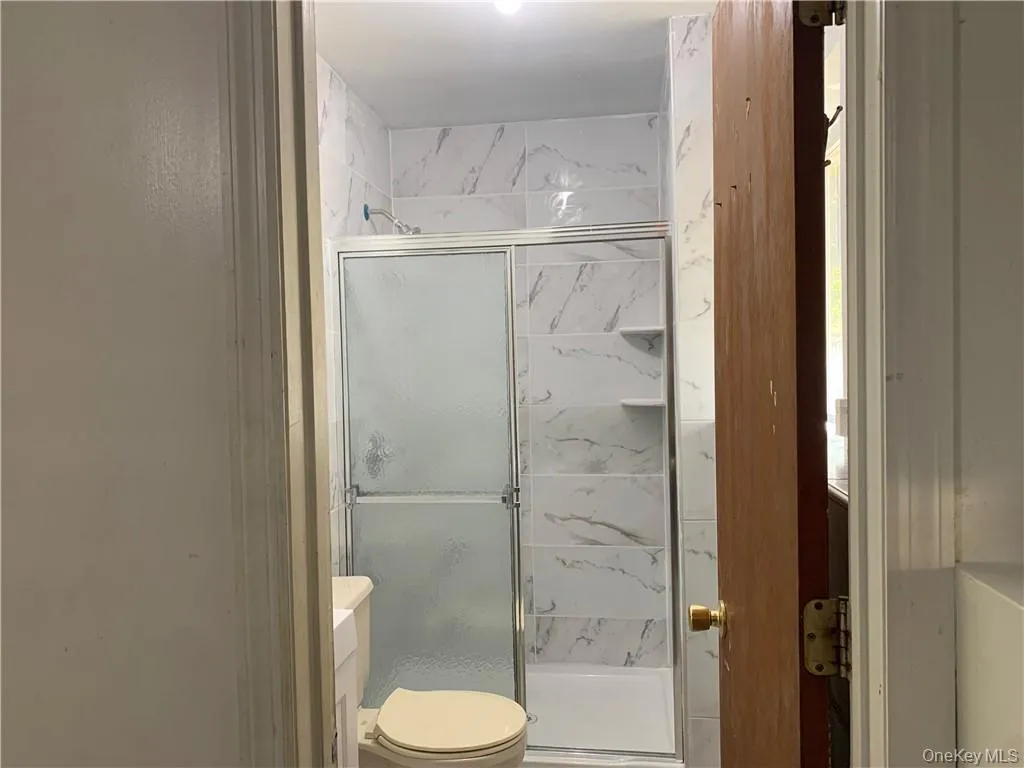 Bathroom featuring vanity, a shower with shower door, and toilet Bathroom featuring vanity, a shower with shower door, and toilet