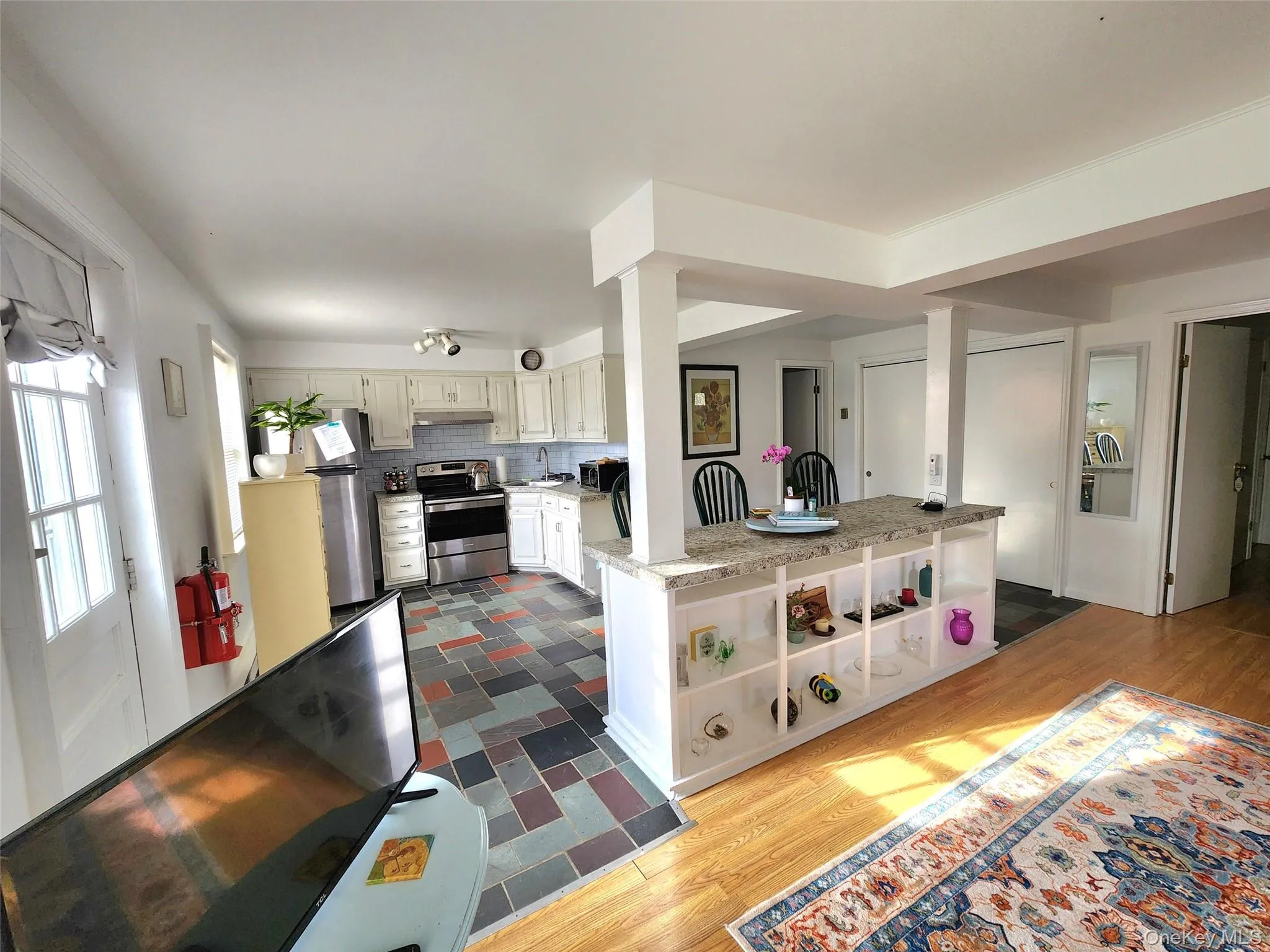 Kitchen with dark wood-style floors, appliances with stainless steel finishes, light countertops, backsplash, and open shelves Kitchen with dark wood-style floors, appliances with stainless steel finishes, light countertops, backsplash, and open shelves