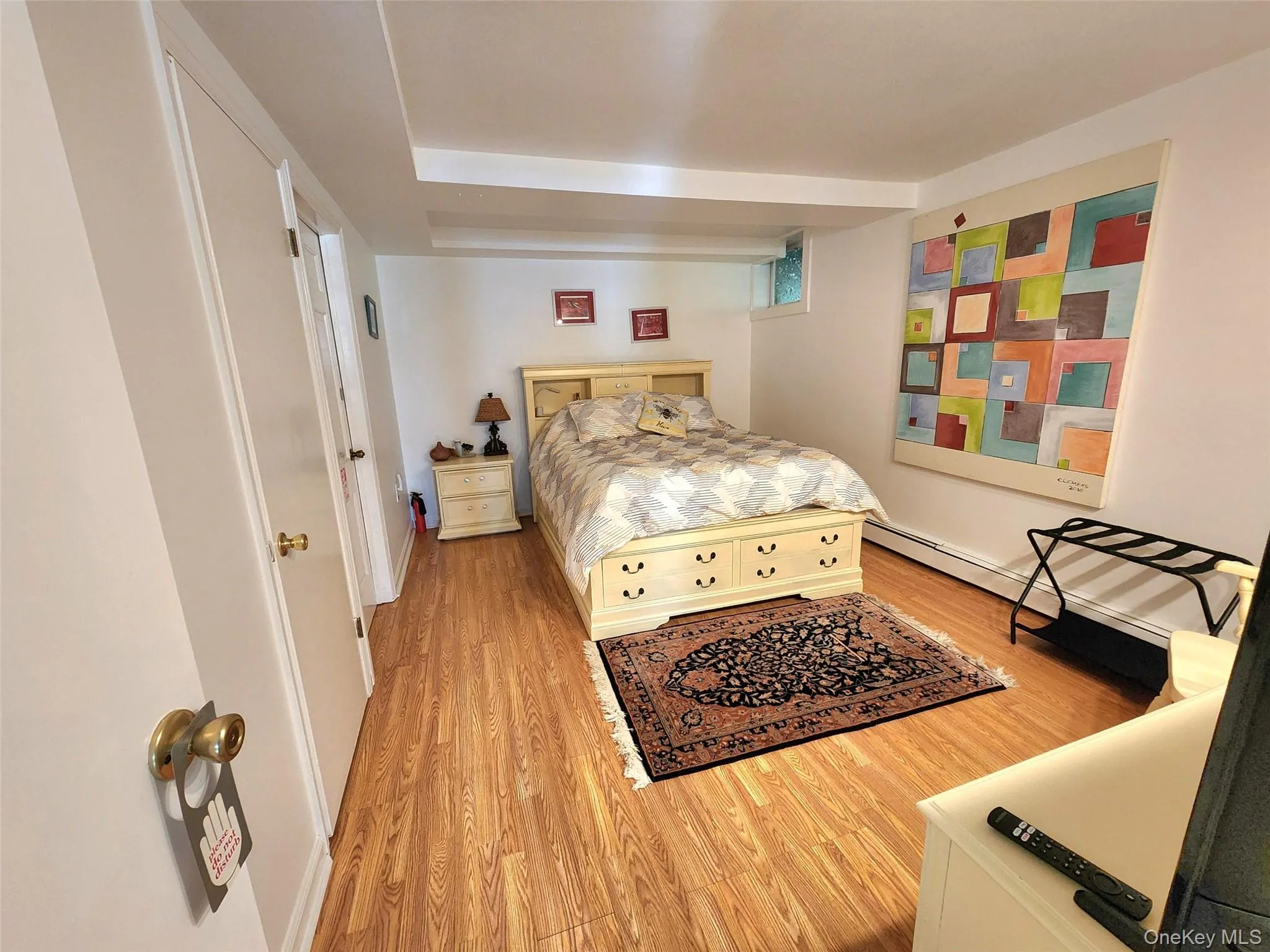 Bedroom with wood finished floors and a baseboard heating unit Bedroom with wood finished floors and a baseboard heating unit