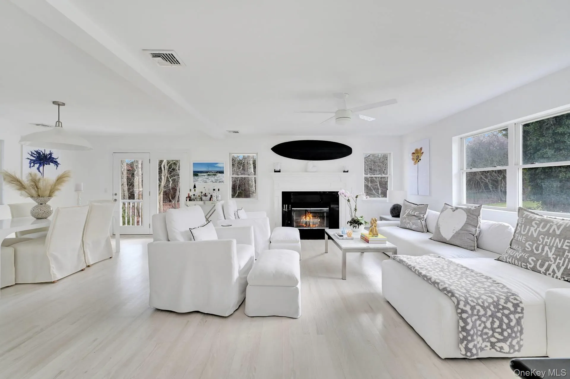 Living area with a glass covered fireplace, light wood-style floors, and ceiling fan Living area with a glass covered fireplace, light wood-style floors, and ceiling fan