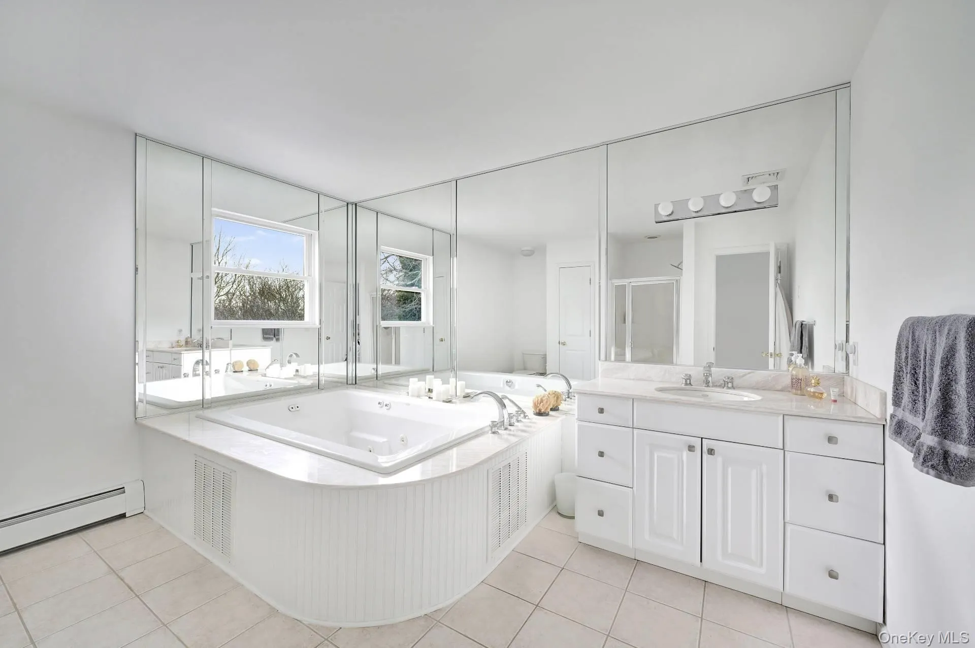 Full bathroom with a stall shower, light tile patterned floors, a tub with jets, and vanity Full bathroom with a stall shower, light tile patterned floors, a tub with jets, and vanity