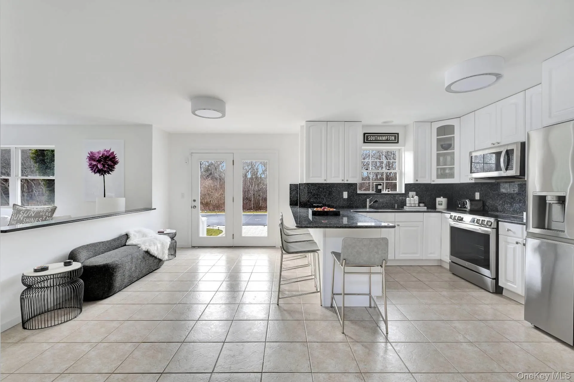 Kitchen with tasteful backsplash, a kitchen breakfast bar, appliances with stainless steel finishes, dark stone countertops, and white cabinets Kitchen with tasteful backsplash, a kitchen breakfast bar, appliances with stainless steel finishes, dark stone countertops, and white cabinets