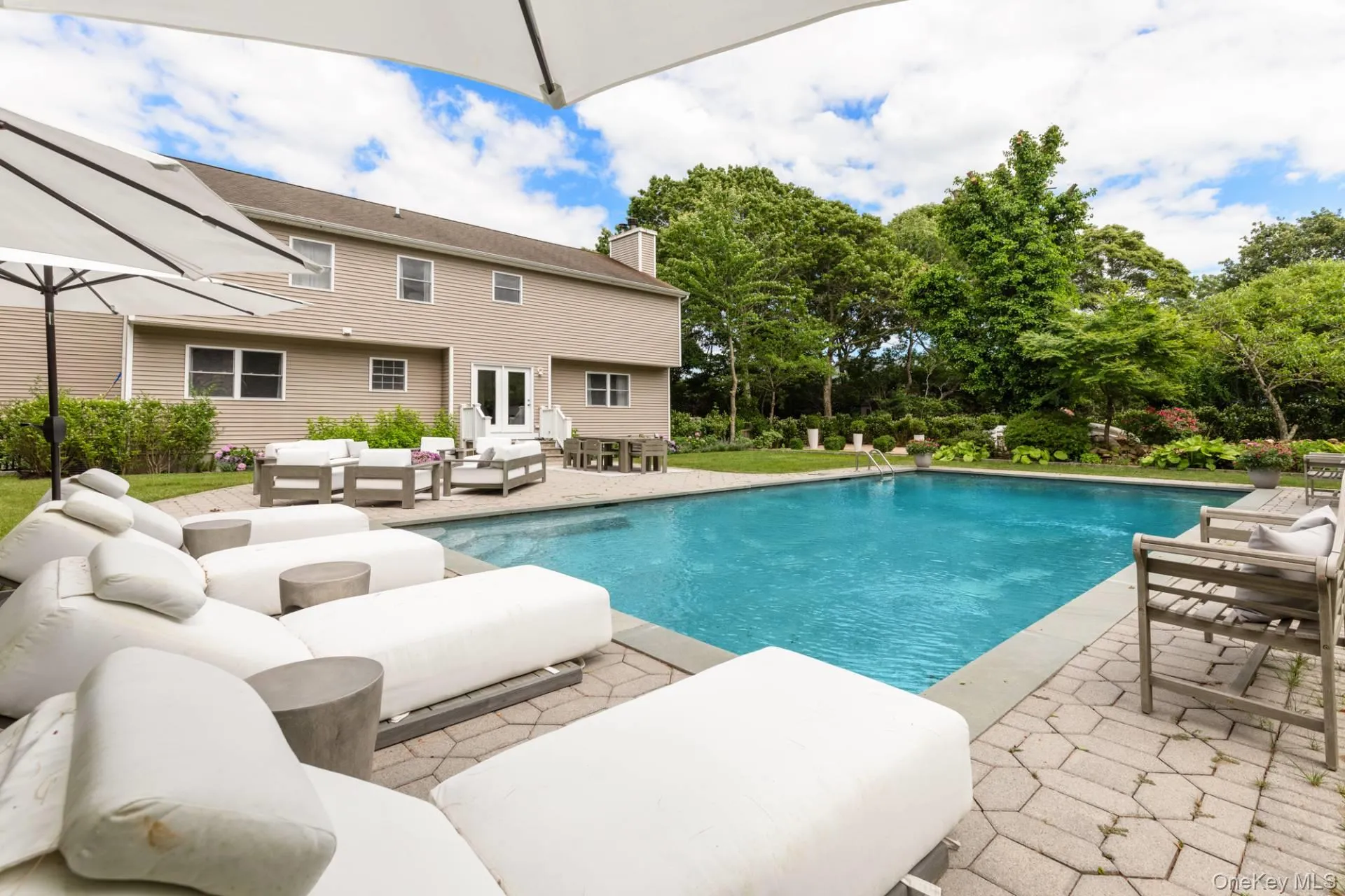 Swimming pool featuring an outdoor hangout area, a patio area, and view of wooded area Swimming pool featuring an outdoor hangout area, a patio area, and view of wooded area