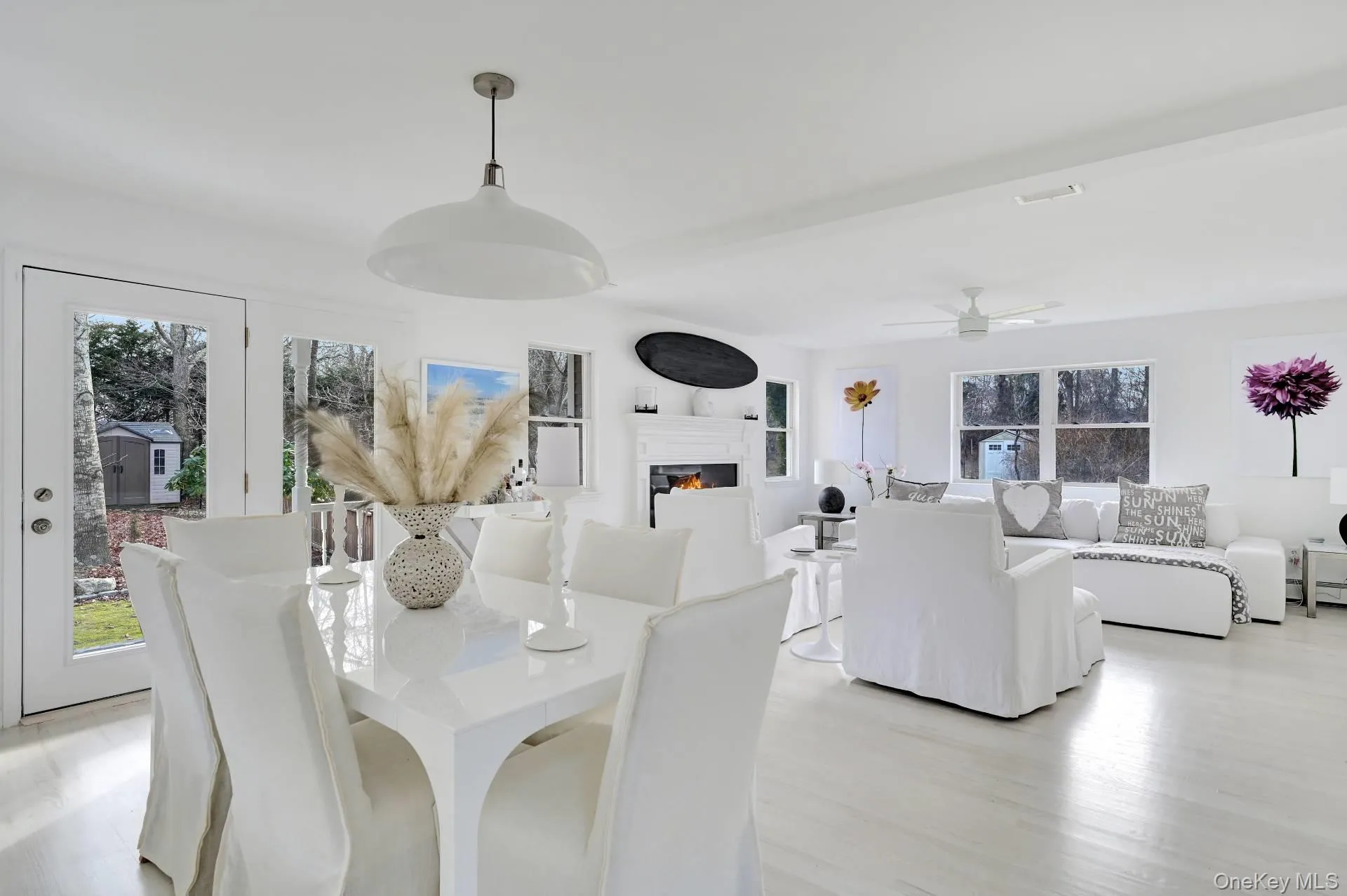 Dining room featuring light wood-style flooring, a lit fireplace, and ceiling fan Dining room featuring light wood-style flooring, a lit fireplace, and ceiling fan