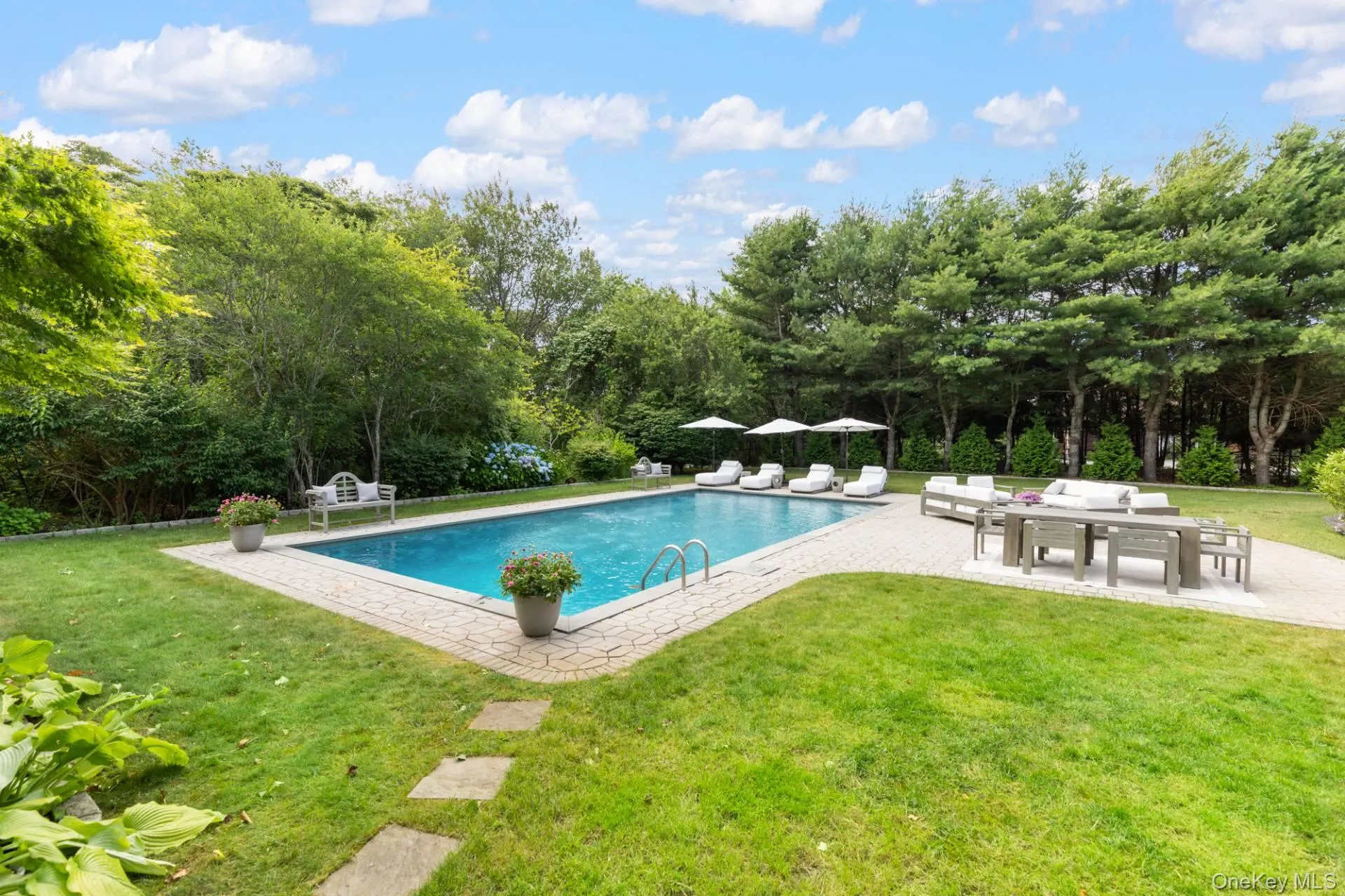 Outdoor pool with a patio area, a yard, view of scattered trees, and outdoor lounge area Outdoor pool with a patio area, a yard, view of scattered trees, and outdoor lounge area