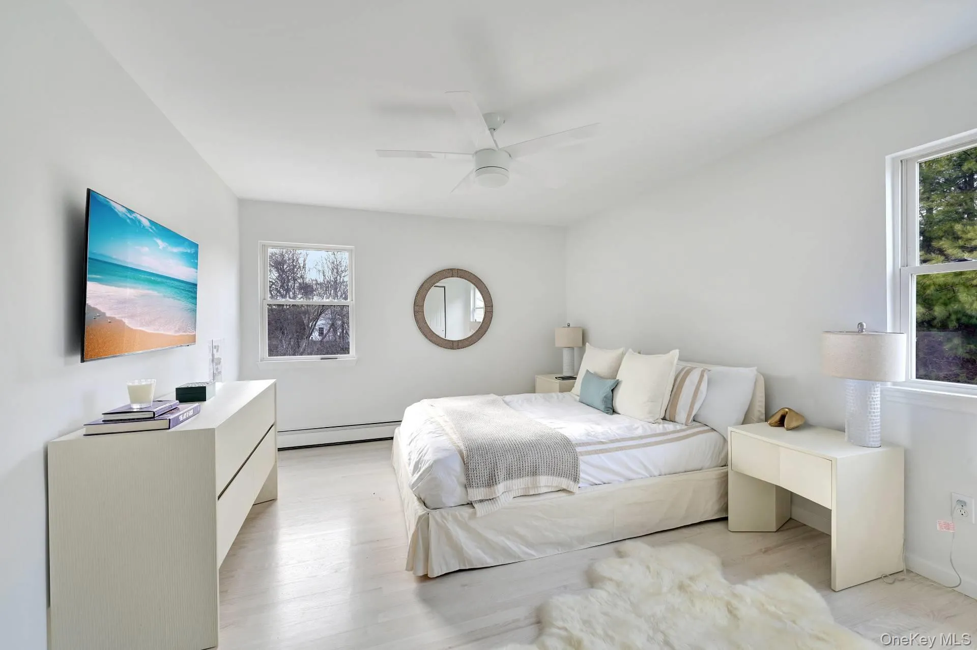Bedroom featuring light wood-style flooring, a ceiling fan, and baseboard heating Bedroom featuring light wood-style flooring, a ceiling fan, and baseboard heating