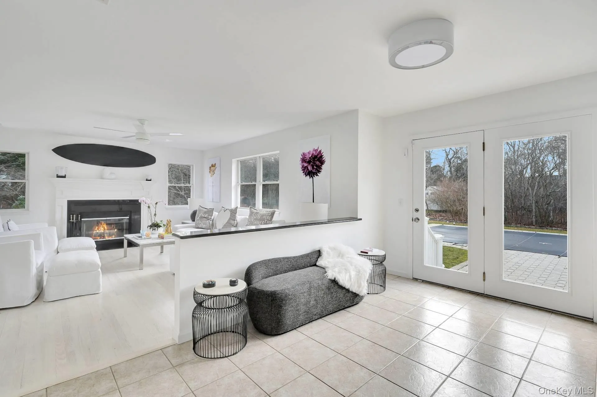 Living room with a ceiling fan, light tile patterned floors, and a glass covered fireplace Living room with a ceiling fan, light tile patterned floors, and a glass covered fireplace