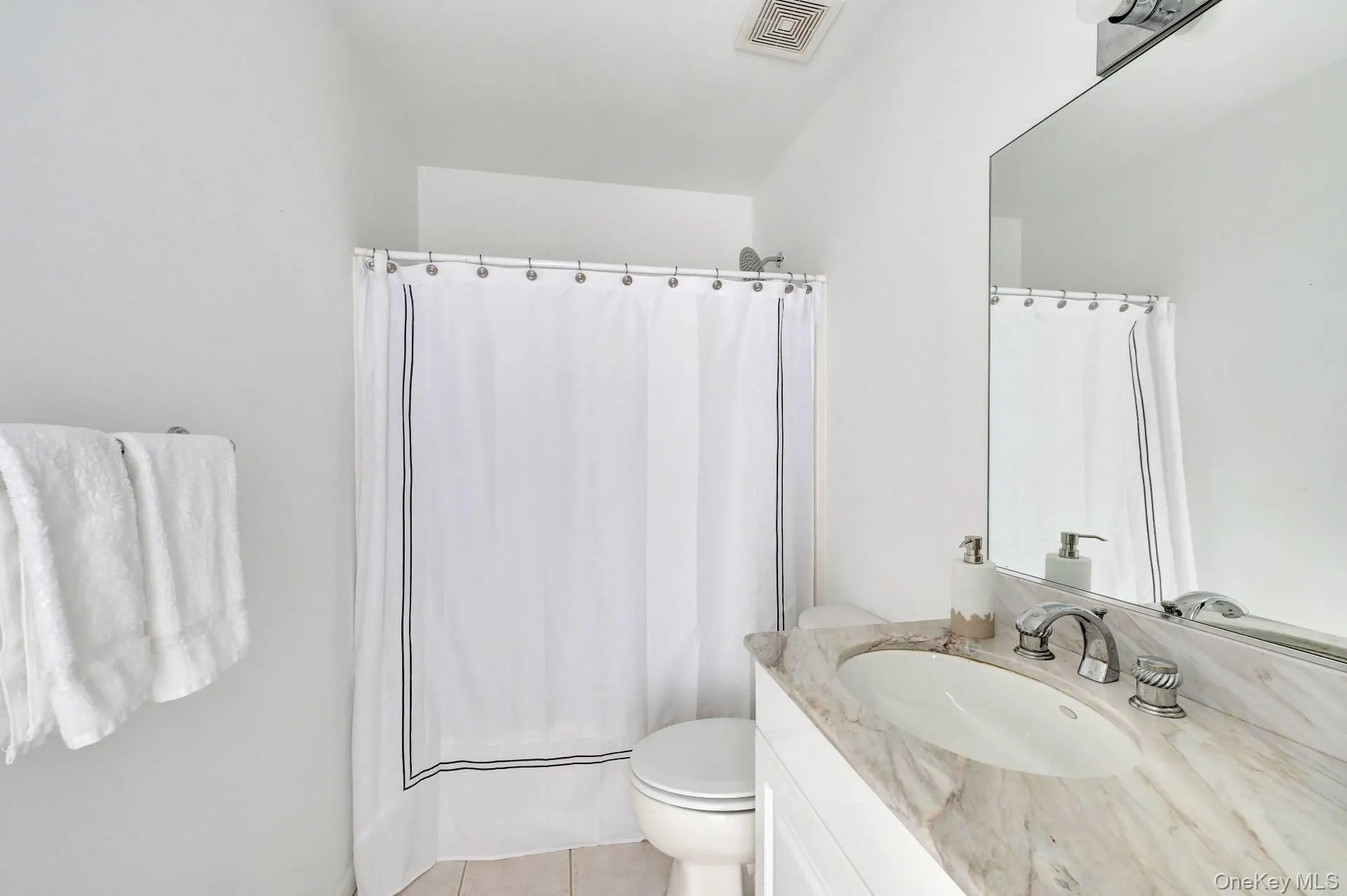 Bathroom with light tile patterned floors, vanity, and shower / bath combination with curtain Bathroom with light tile patterned floors, vanity, and shower / bath combination with curtain