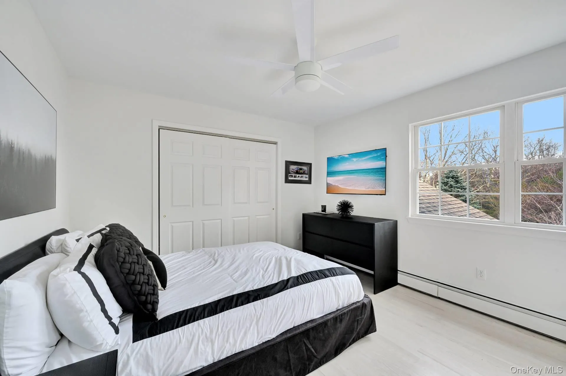 Bedroom featuring baseboard heating, wood finished floors, a closet, and ceiling fan Bedroom featuring baseboard heating, wood finished floors, a closet, and ceiling fan