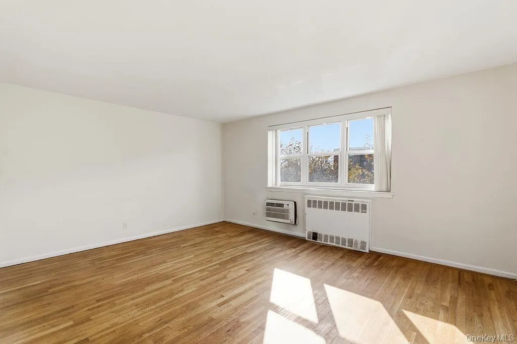 Unfurnished room with radiator and light wood-style flooring Unfurnished room with radiator and light wood-style flooring