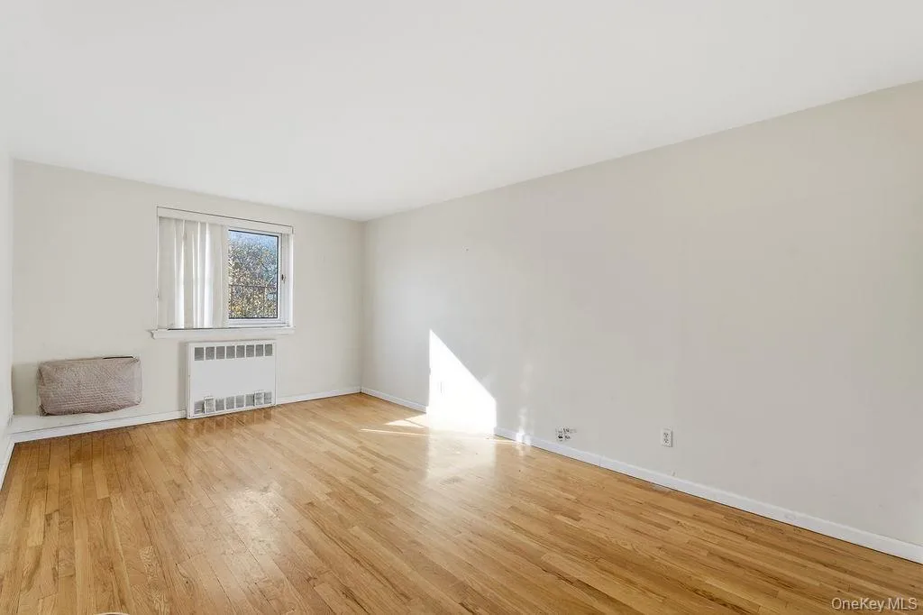 Spare room featuring light wood-type flooring and radiator heating unit Spare room featuring light wood-type flooring and radiator heating unit
