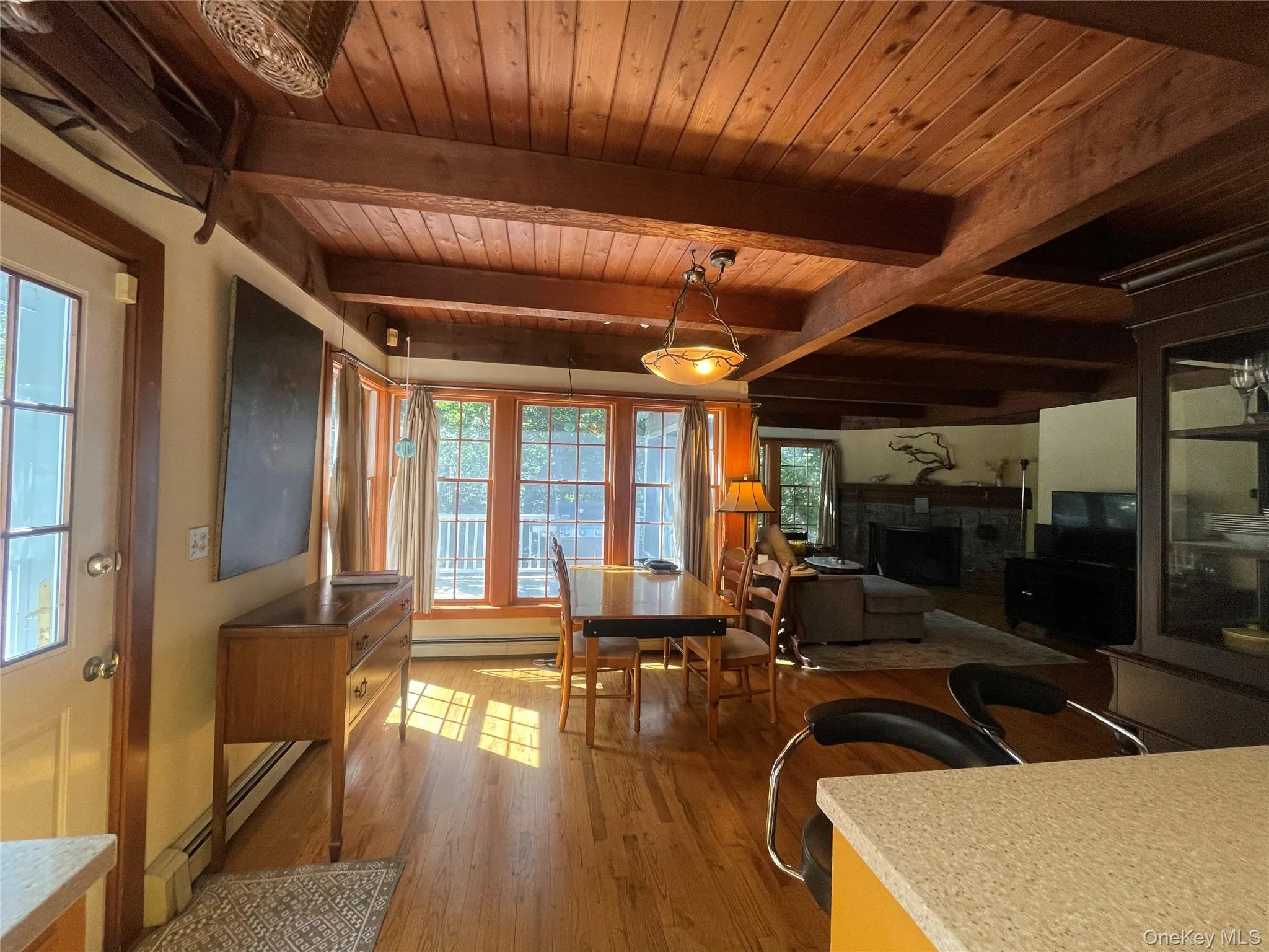 Dining area with a fireplace, light wood-style flooring, baseboard heating, and a wood ceiling with exposed beams Dining area with a fireplace, light wood-style flooring, baseboard heating, and a wood ceiling with exposed beams