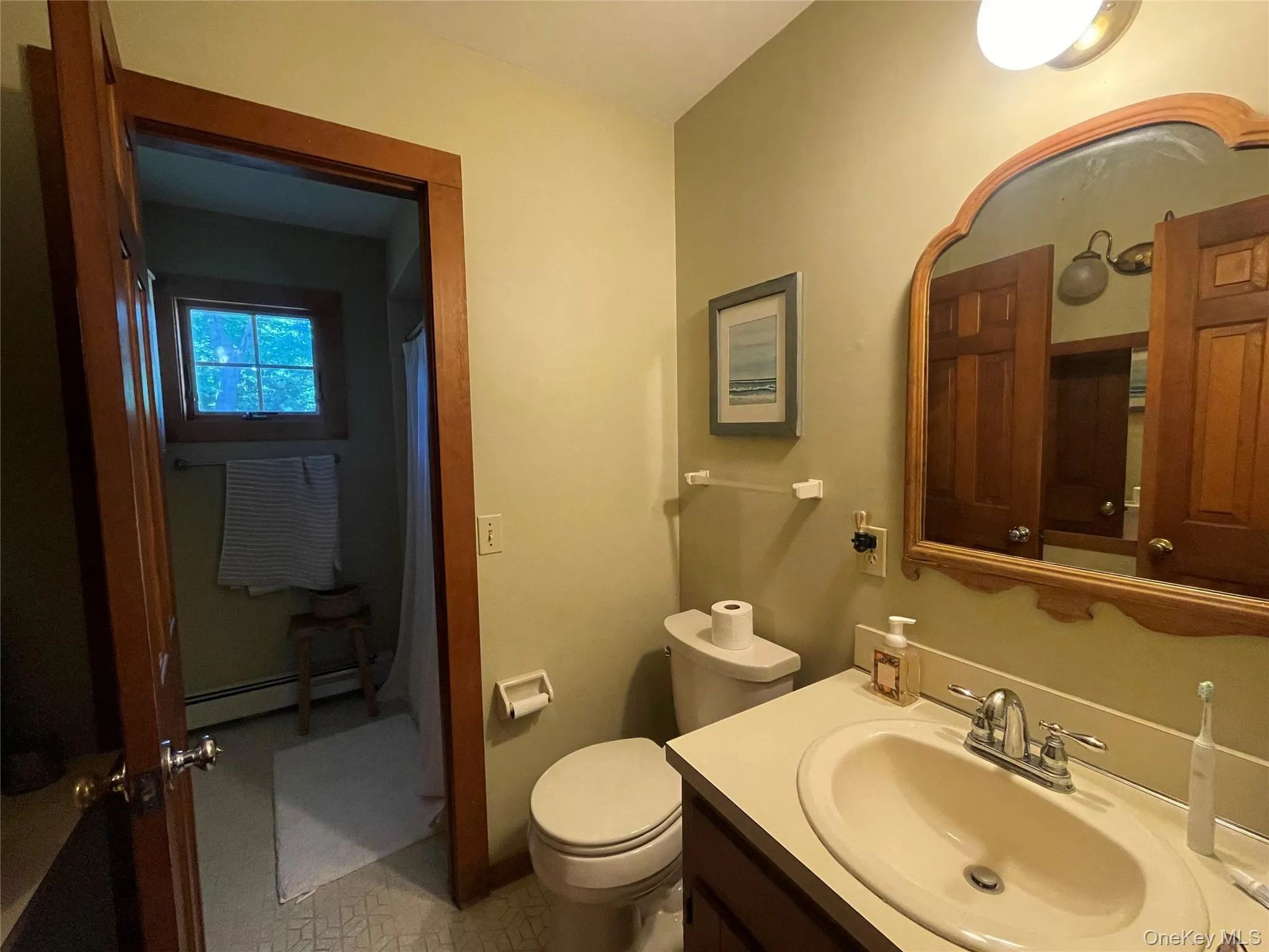 Full bathroom with vanity, a shower with shower curtain, and a baseboard radiator Full bathroom with vanity, a shower with shower curtain, and a baseboard radiator
