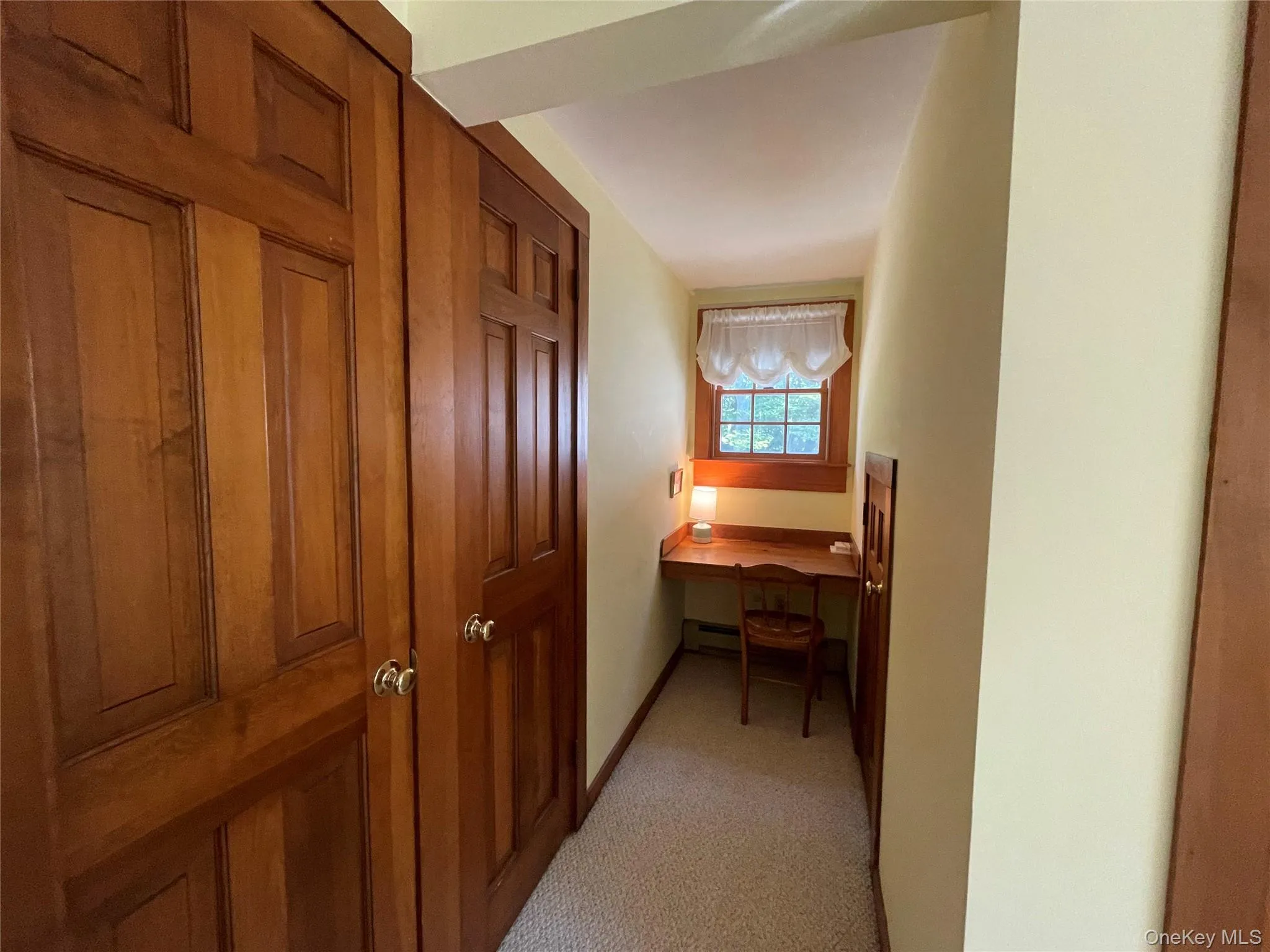Corridor featuring an office area and light colored carpet Corridor featuring an office area and light colored carpet