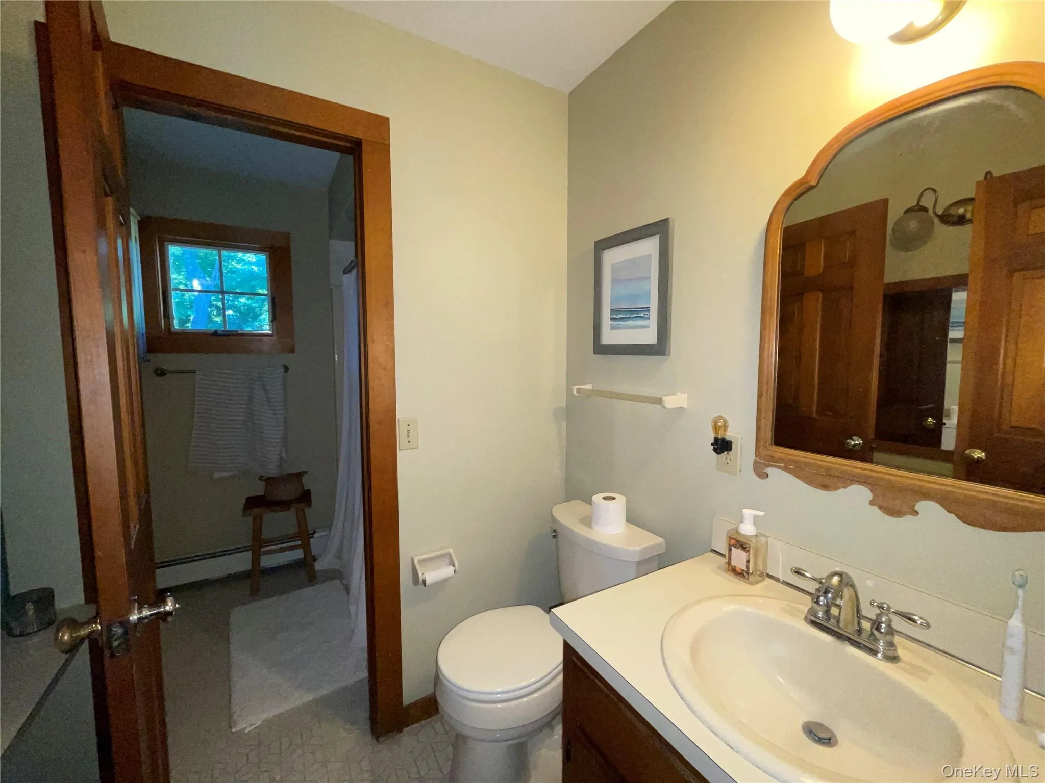 Full bathroom with vanity, a baseboard heating unit, and a shower with shower curtain Full bathroom with vanity, a baseboard heating unit, and a shower with shower curtain