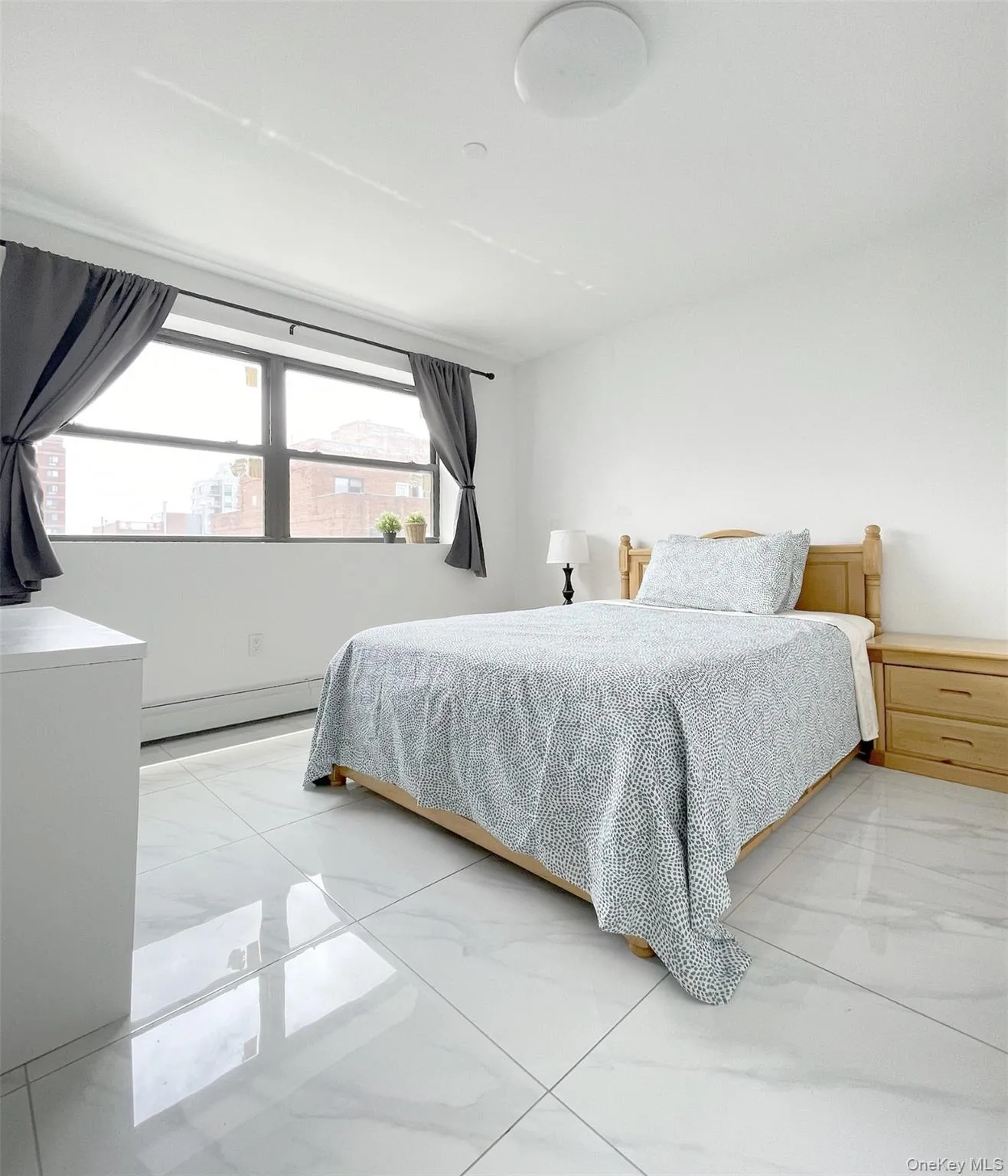 Bedroom with marble look tile flooring and baseboard heating Bedroom with marble look tile flooring and baseboard heating