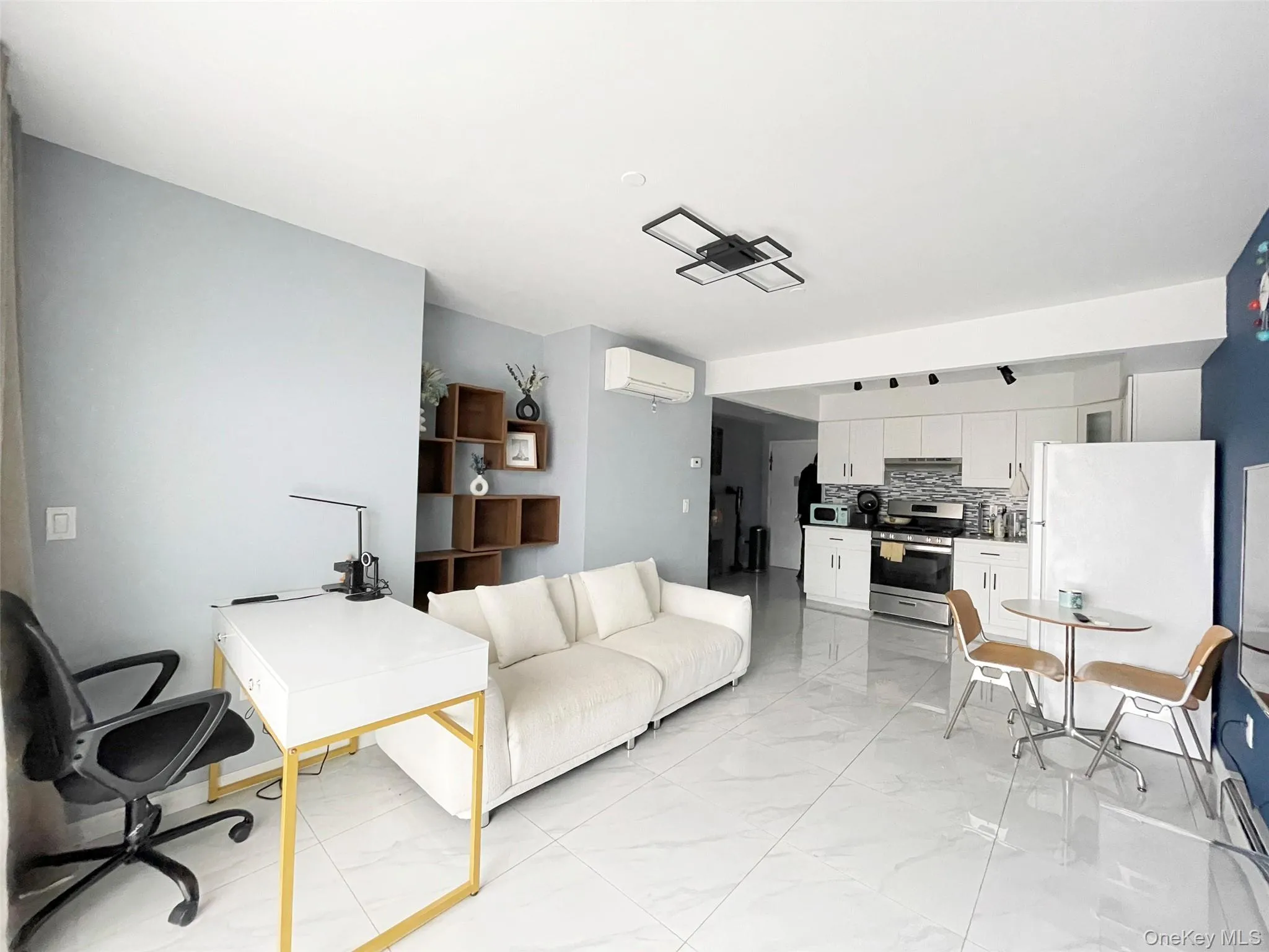 Living area featuring light marble finish floors, an AC wall unit, and an office area Living area featuring light marble finish floors, an AC wall unit, and an office area