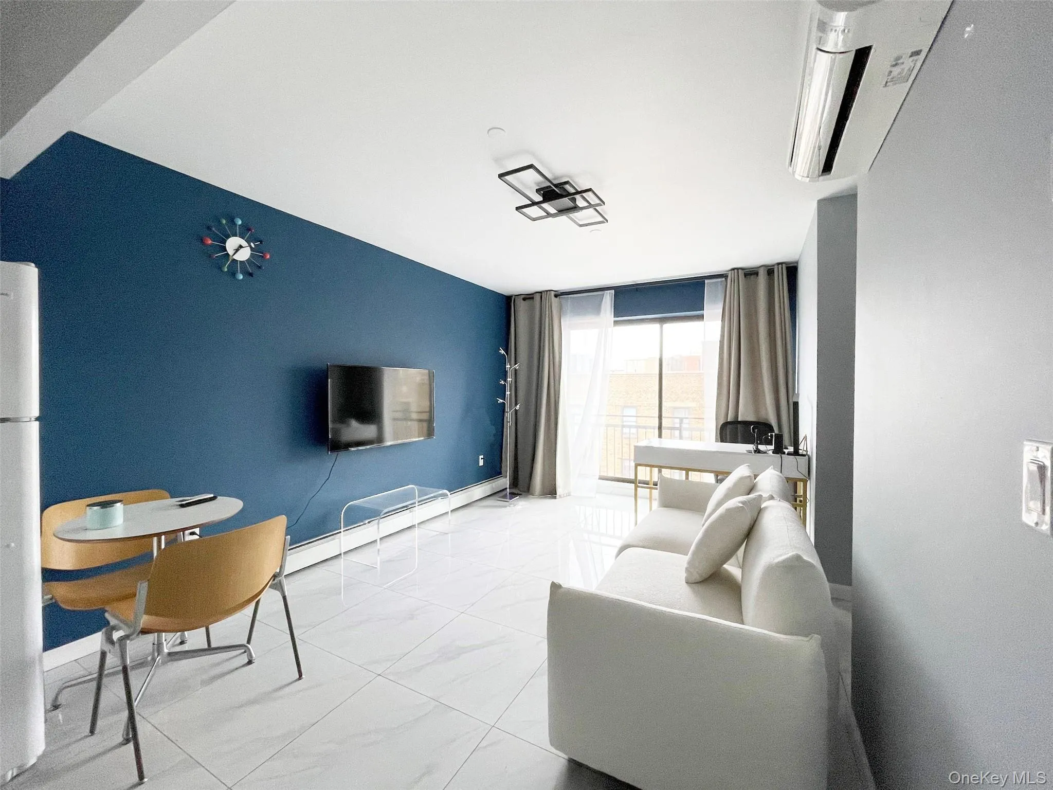 Living area with a wall of windows, a baseboard radiator, and light marble finish flooring Living area with a wall of windows, a baseboard radiator, and light marble finish flooring