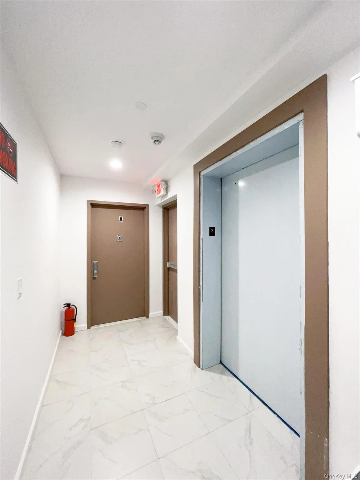 Hall featuring light marble finish flooring and elevator Hall featuring light marble finish flooring and elevator