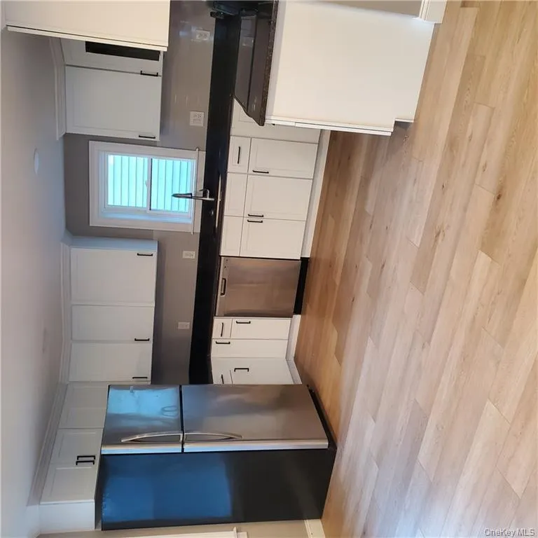 Kitchen featuring fridge, white cabinetry, stainless steel dishwasher, and dark stone counters Kitchen featuring fridge, white cabinetry, stainless steel dishwasher, and dark stone counters