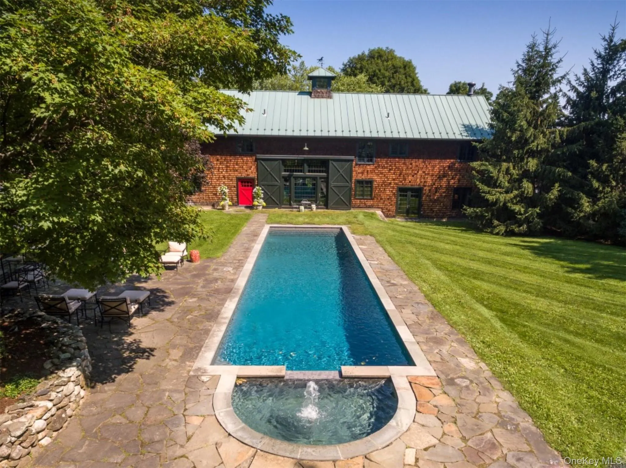 Back of house with a yard, a metal roof, brick siding, and a pool with connected hot tub Back of house with a yard, a metal roof, brick siding, and a pool with connected hot tub