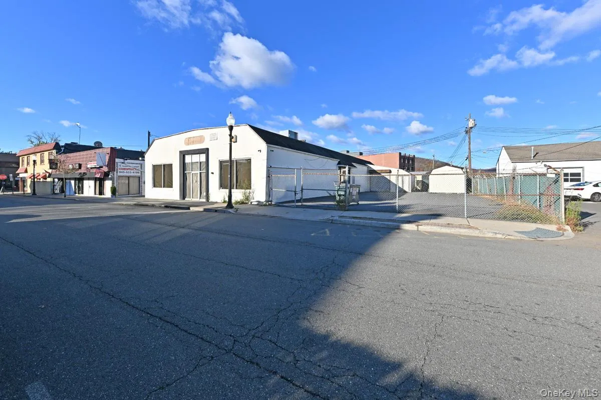 View of asphalt road with curbs, sidewalks, street lighting, and a gate View of asphalt road with curbs, sidewalks, street lighting, and a gate