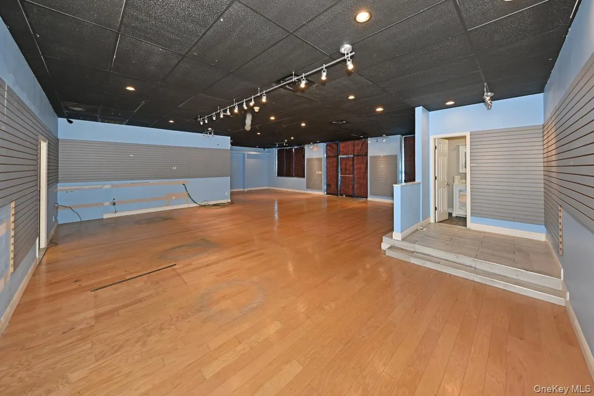 Unfurnished living room featuring light wood-type flooring, rail lighting, a drop ceiling, and recessed lighting Unfurnished living room featuring light wood-type flooring, rail lighting, a drop ceiling, and recessed lighting