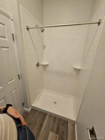 Full bathroom featuring a shower stall and dark wood-style flooring Full bathroom featuring a shower stall and dark wood-style flooring
