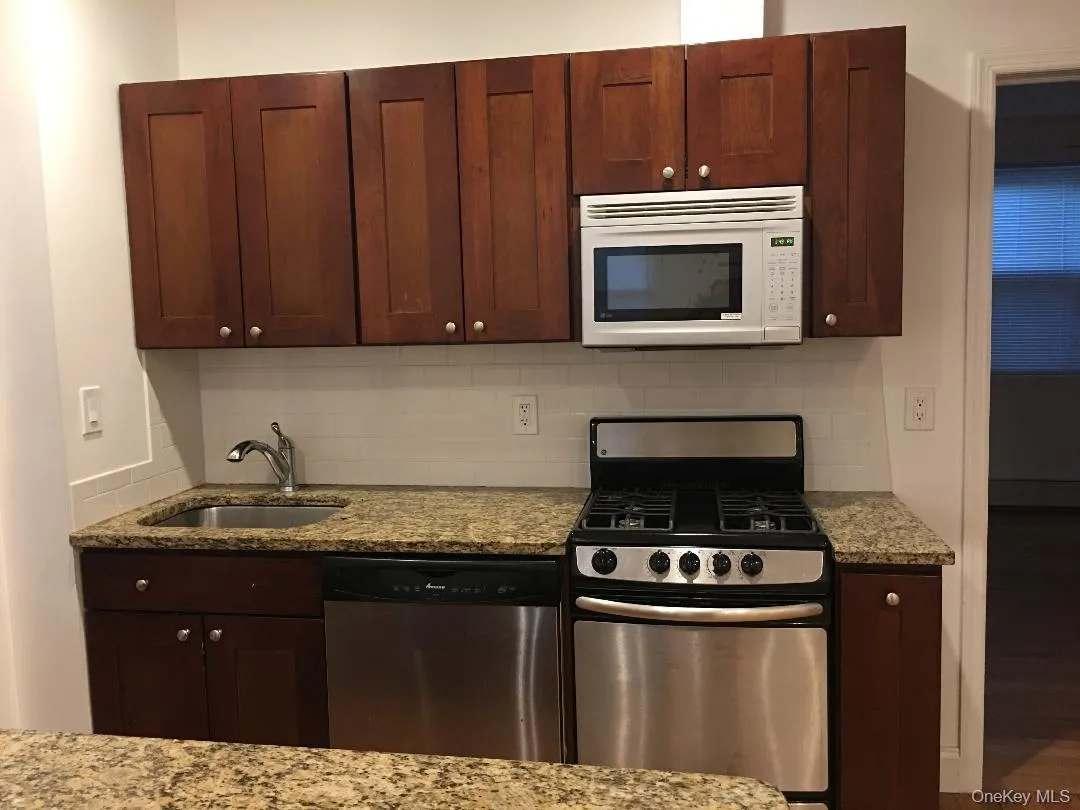 Kitchen featuring stainless steel appliances, tasteful backsplash, and light stone countertops Kitchen featuring stainless steel appliances, tasteful backsplash, and light stone countertops