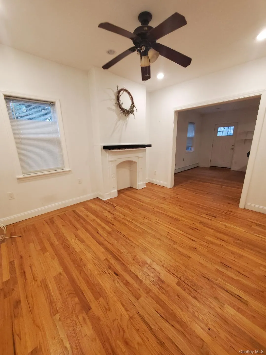 Unfurnished living room with light wood-type flooring, healthy amount of natural light, a baseboard heating unit, recessed lighting, and a ceiling fan Unfurnished living room with light wood-type flooring, healthy amount of natural light, a baseboard heating unit, recessed lighting, and a ceiling fan