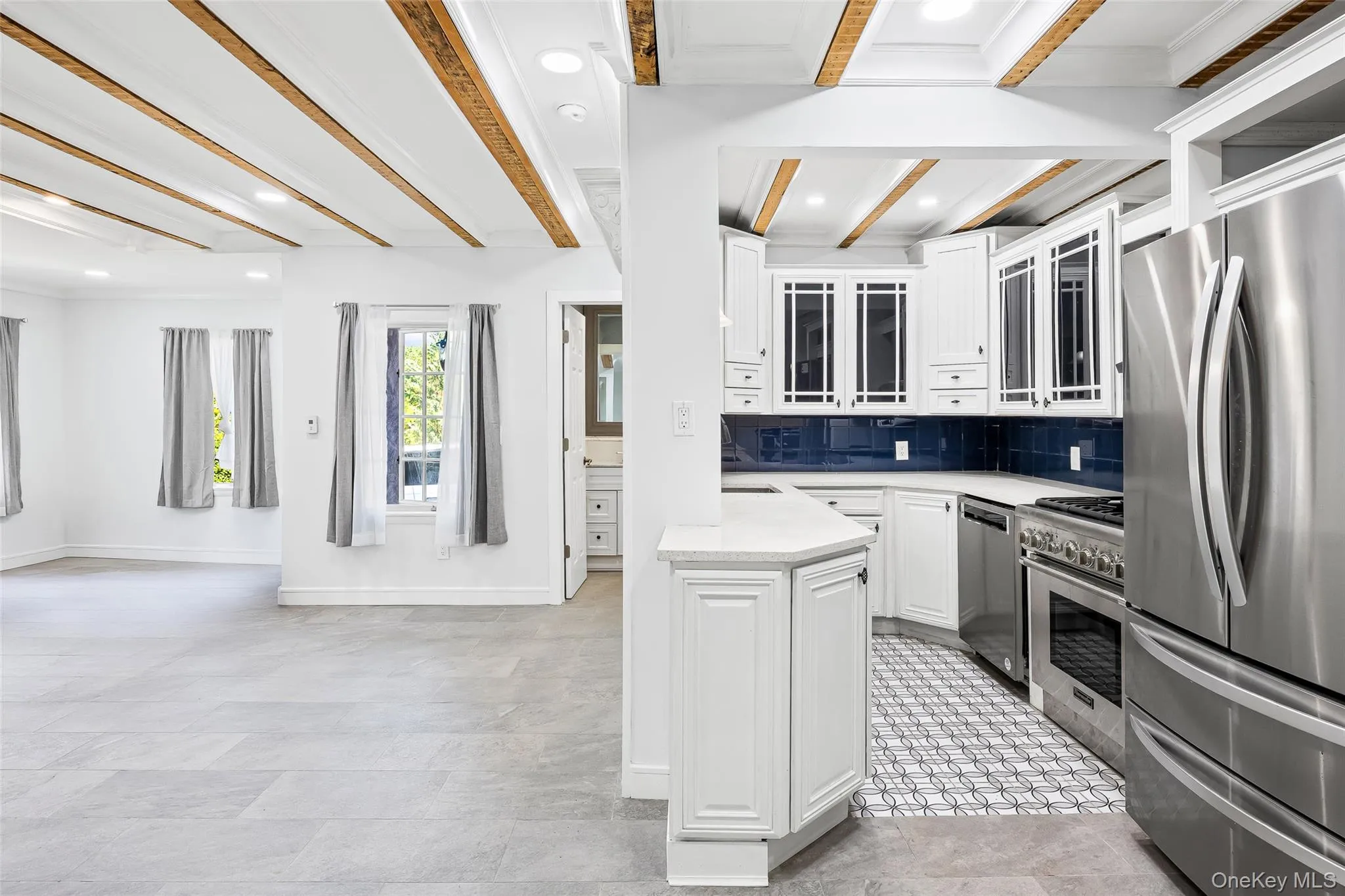 Kitchen with white cabinets, beam ceiling, stainless steel appliances, tasteful backsplash, and recessed lighting Kitchen with white cabinets, beam ceiling, stainless steel appliances, tasteful backsplash, and recessed lighting