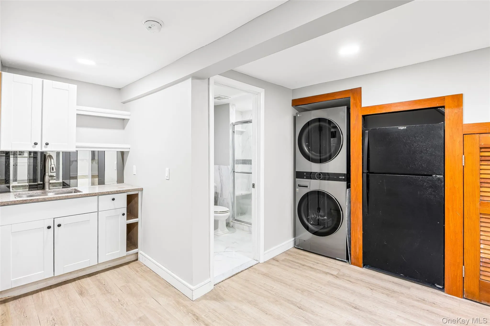 Laundry area featuring estacked washer and dryer and light wood-style flooring Laundry area featuring estacked washer and dryer and light wood-style flooring
