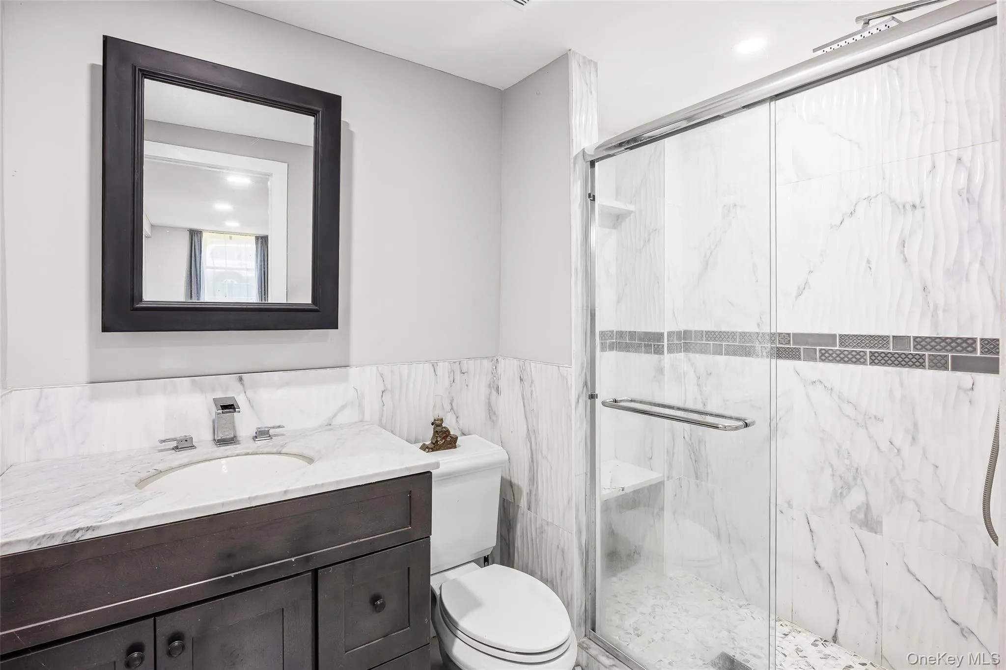 Bathroom featuring a marble finish shower, vanity, and recessed lighting Bathroom featuring a marble finish shower, vanity, and recessed lighting