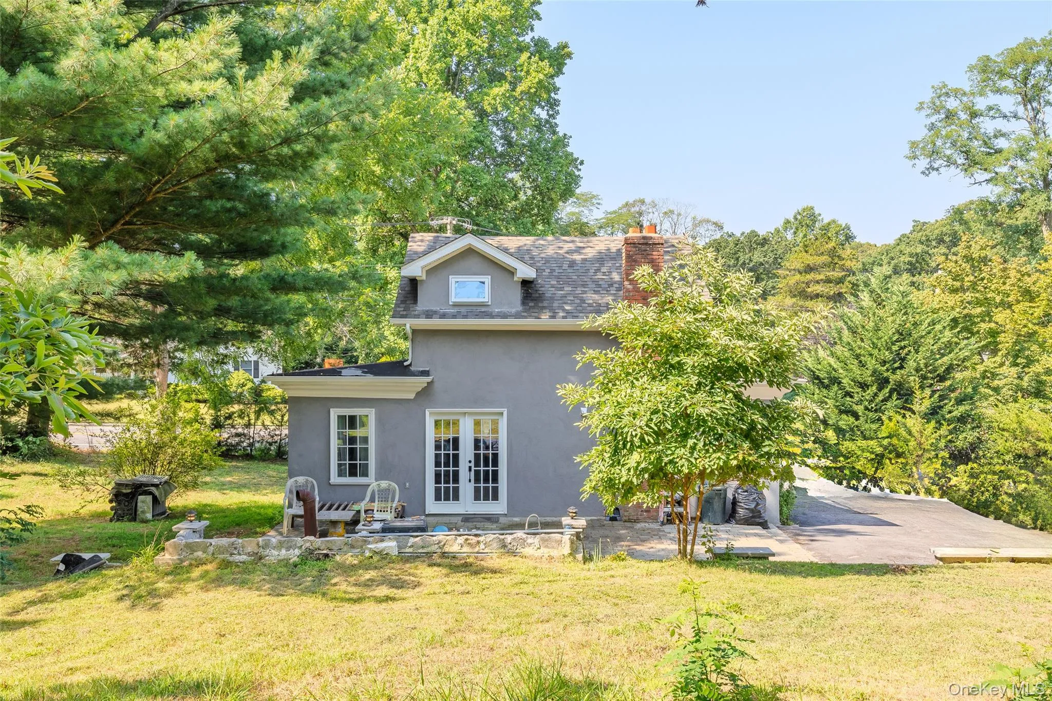 Rear view of house with a chimney, a patio area, stucco siding, french doors, and a yard Rear view of house with a chimney, a patio area, stucco siding, french doors, and a yard