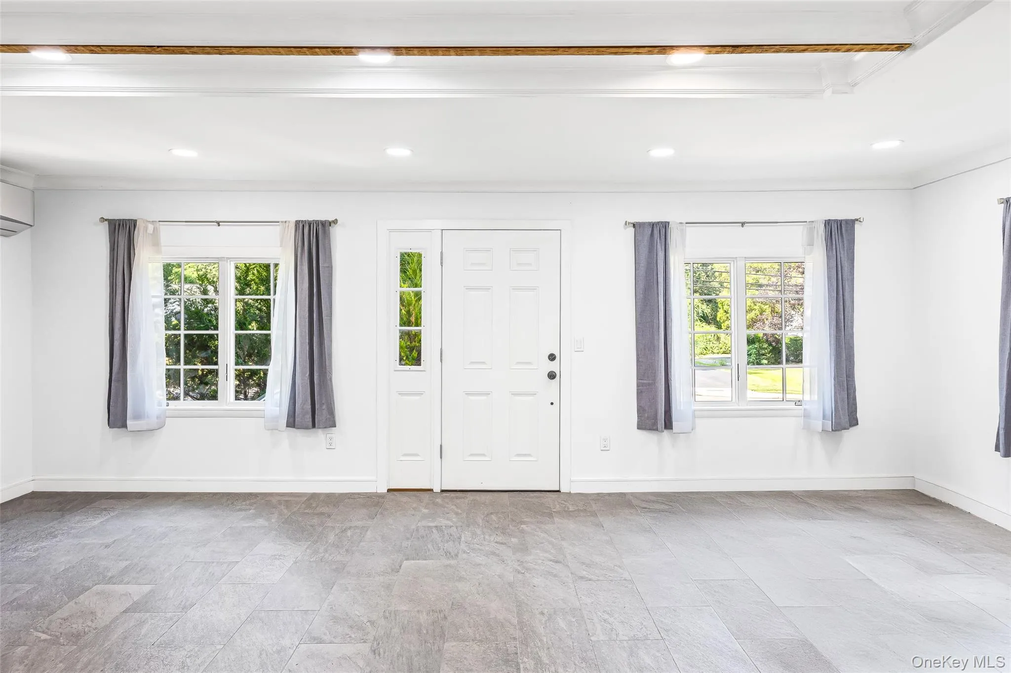 Entryway with crown molding, recessed lighting, a wall mounted air conditioner, and light stone finish floors Entryway with crown molding, recessed lighting, a wall mounted air conditioner, and light stone finish floors