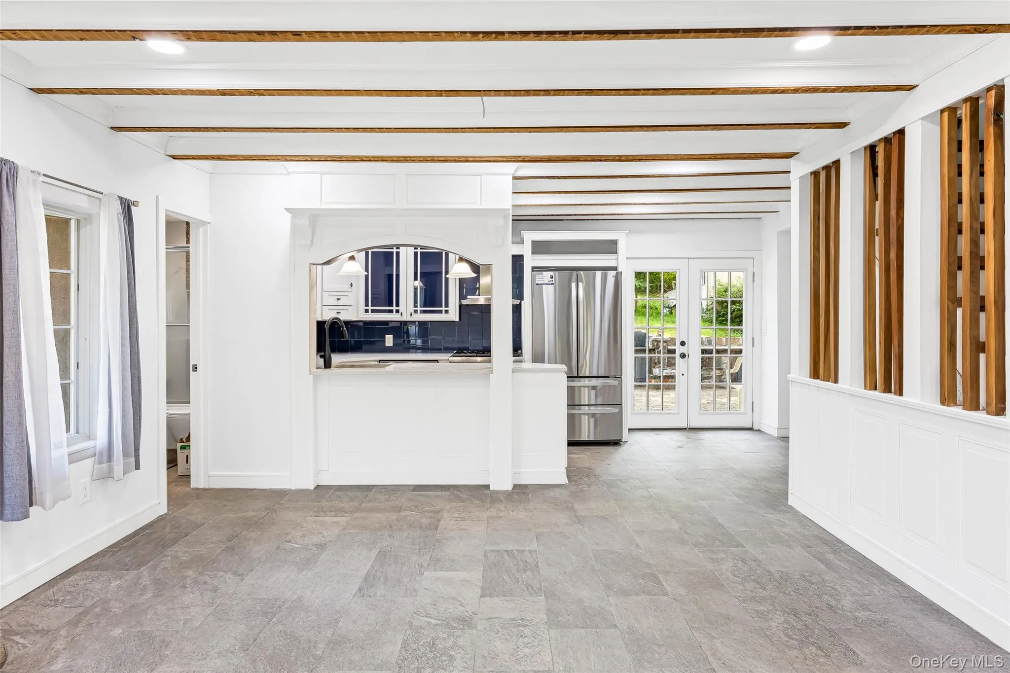Unfurnished living room featuring beam ceiling, french doors, light stone finish floors, and recessed lighting Unfurnished living room featuring beam ceiling, french doors, light stone finish floors, and recessed lighting