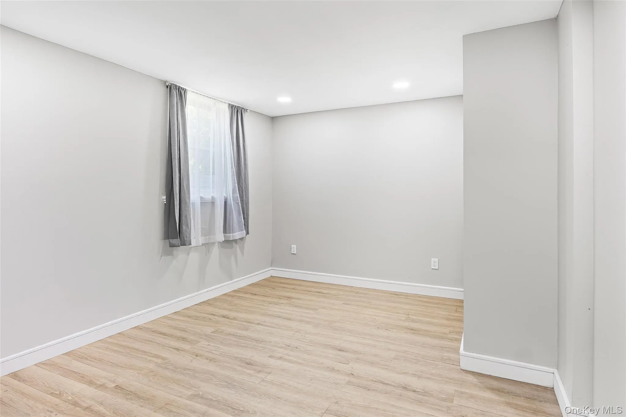 Spare room featuring light wood-style floors and baseboards Spare room featuring light wood-style floors and baseboards