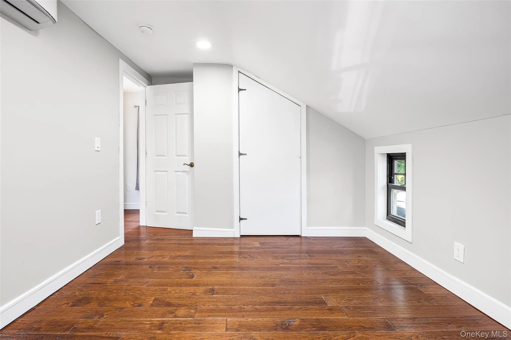 Bonus room featuring dark wood-style floors, a wall mounted AC, and lofted ceiling Bonus room featuring dark wood-style floors, a wall mounted AC, and lofted ceiling