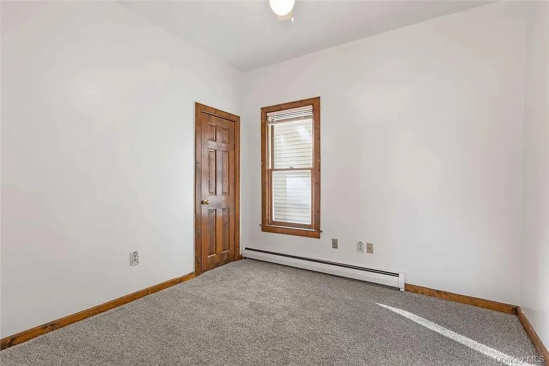 Unfurnished room featuring a baseboard radiator and carpet floors Unfurnished room featuring a baseboard radiator and carpet floors