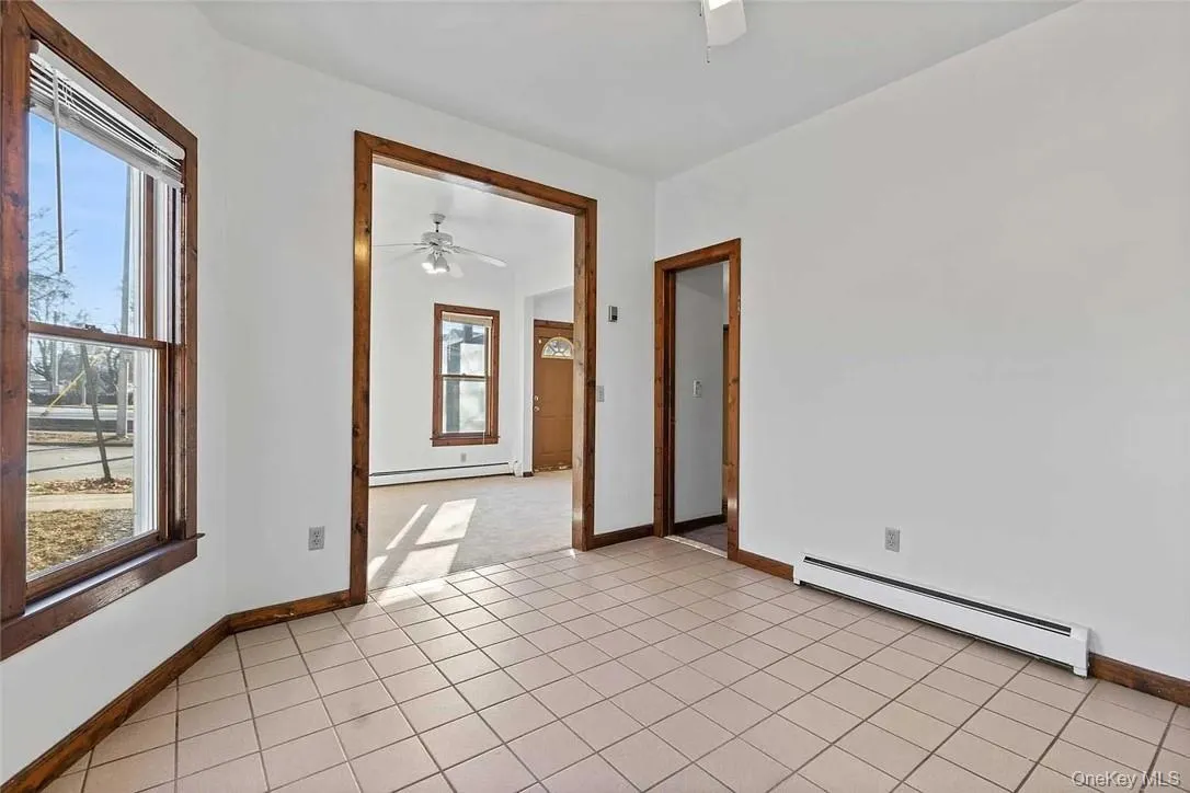 Spare room featuring a baseboard heating unit, light tile patterned floors, and ceiling fan Spare room featuring a baseboard heating unit, light tile patterned floors, and ceiling fan