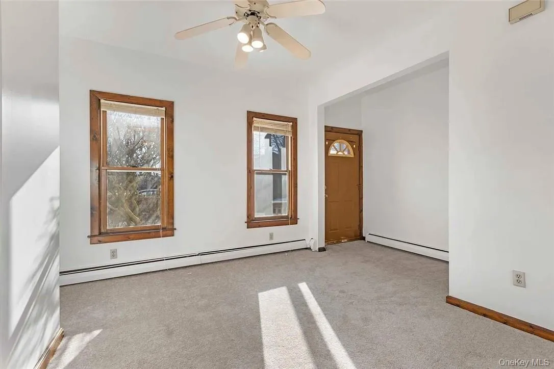 Unfurnished room with baseboard heating, light colored carpet, and ceiling fan Unfurnished room with baseboard heating, light colored carpet, and ceiling fan