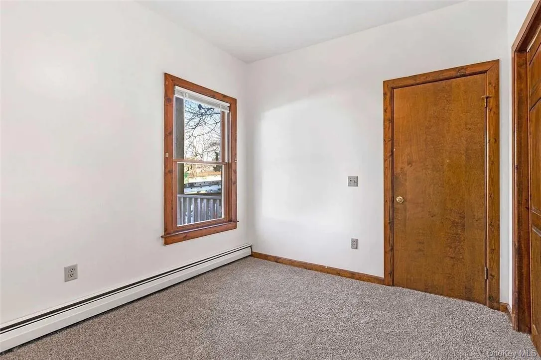 Spare room featuring a baseboard heating unit and carpet floors Spare room featuring a baseboard heating unit and carpet floors