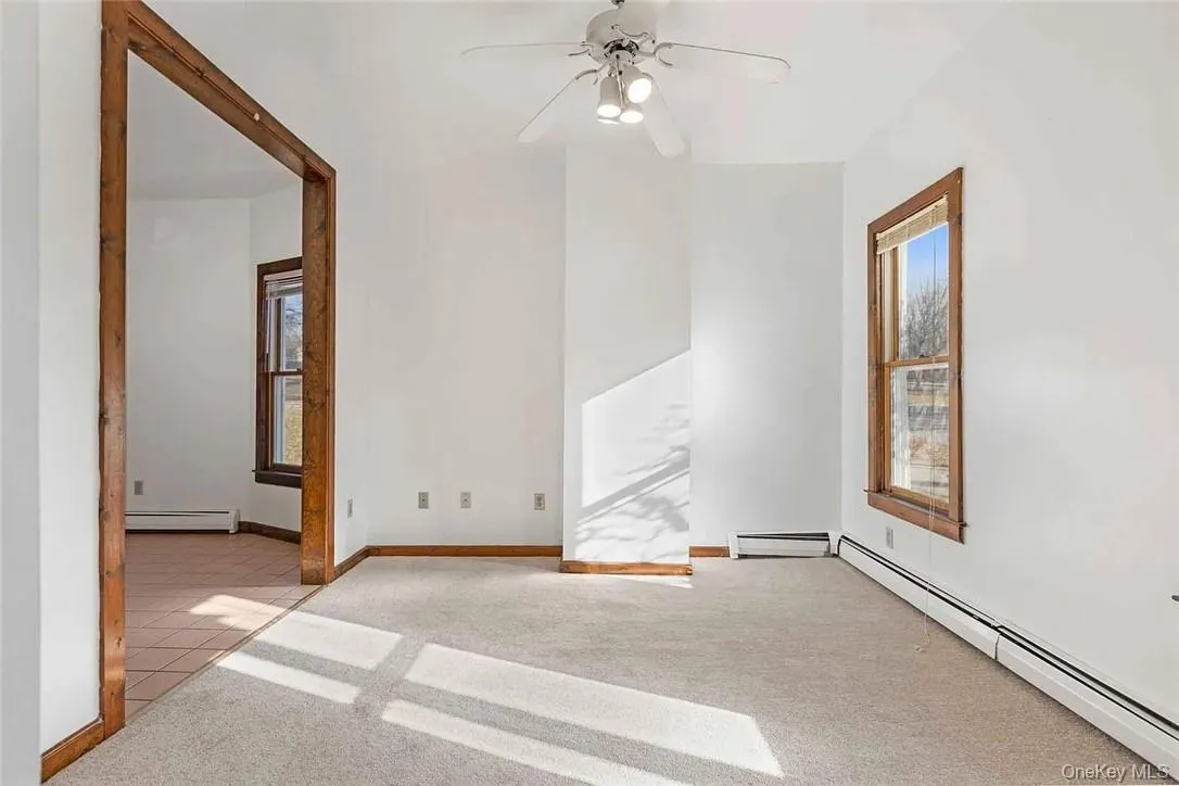 Spare room with light carpet, a baseboard radiator, and ceiling fan Spare room with light carpet, a baseboard radiator, and ceiling fan