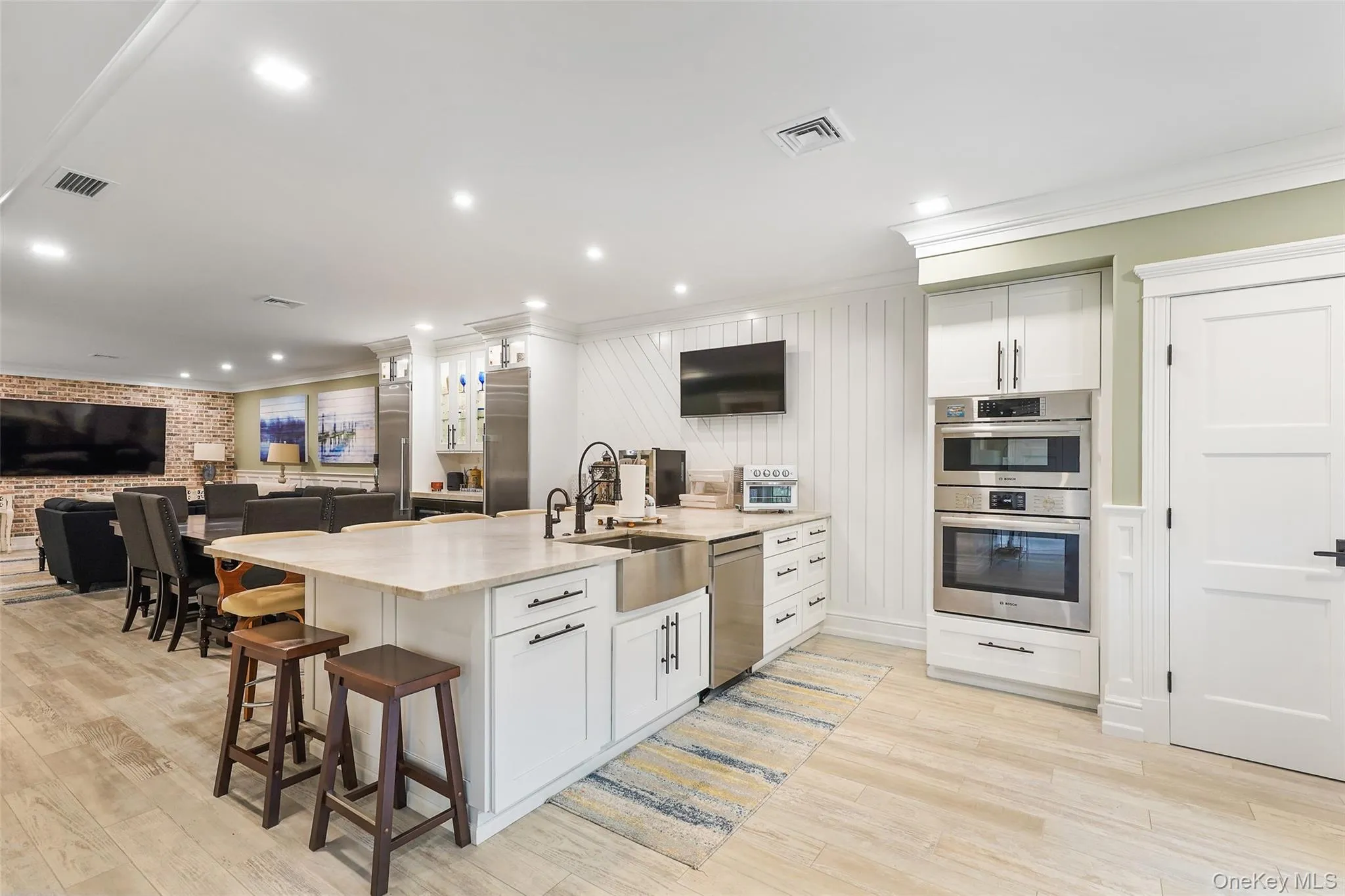 Kitchen featuring a kitchen breakfast bar, open floor plan, crown molding, white cabinets, and recessed lighting Kitchen featuring a kitchen breakfast bar, open floor plan, crown molding, white cabinets, and recessed lighting
