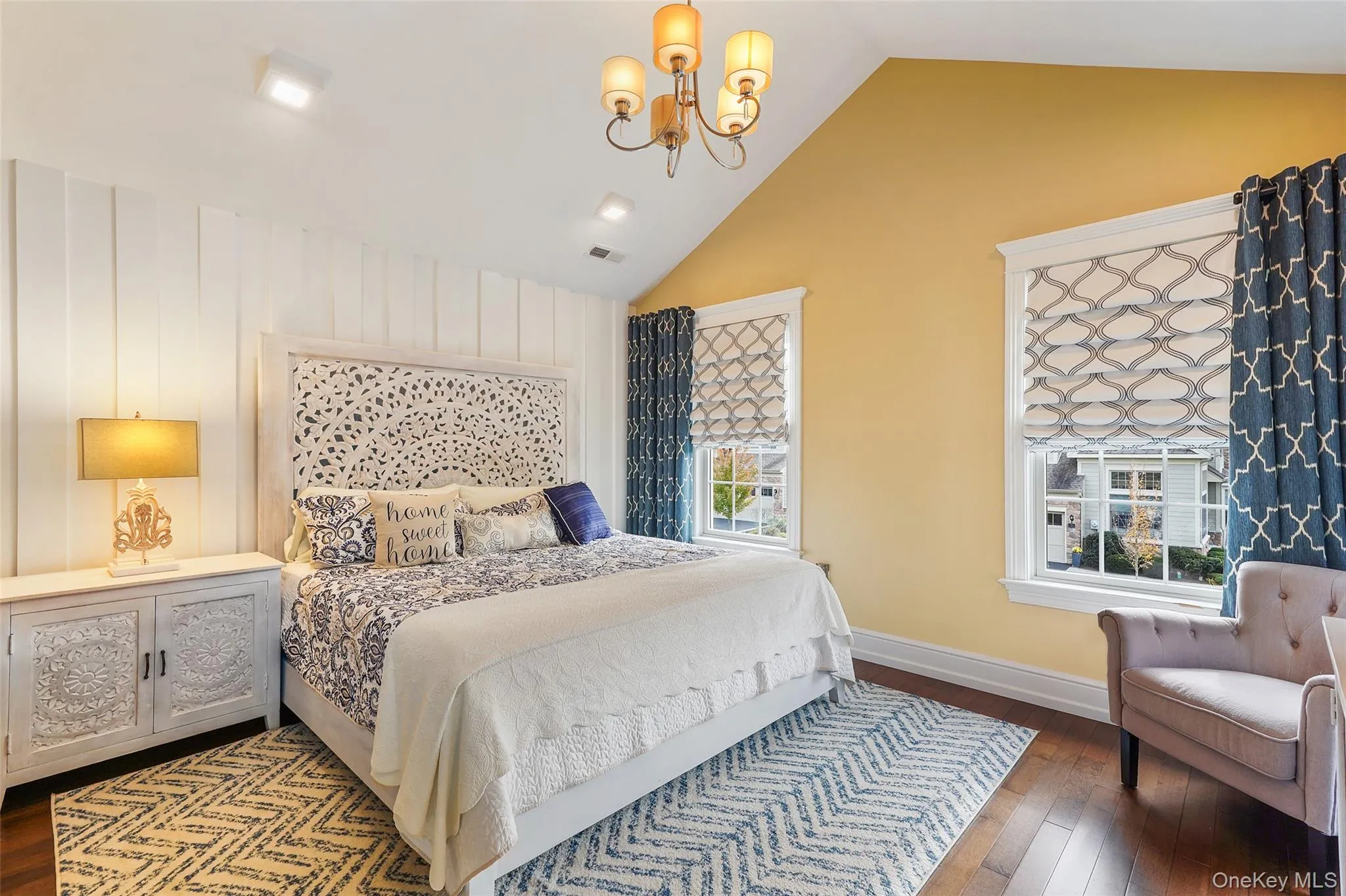 Bedroom featuring dark wood-type flooring, a chandelier, and lofted ceiling Bedroom featuring dark wood-type flooring, a chandelier, and lofted ceiling